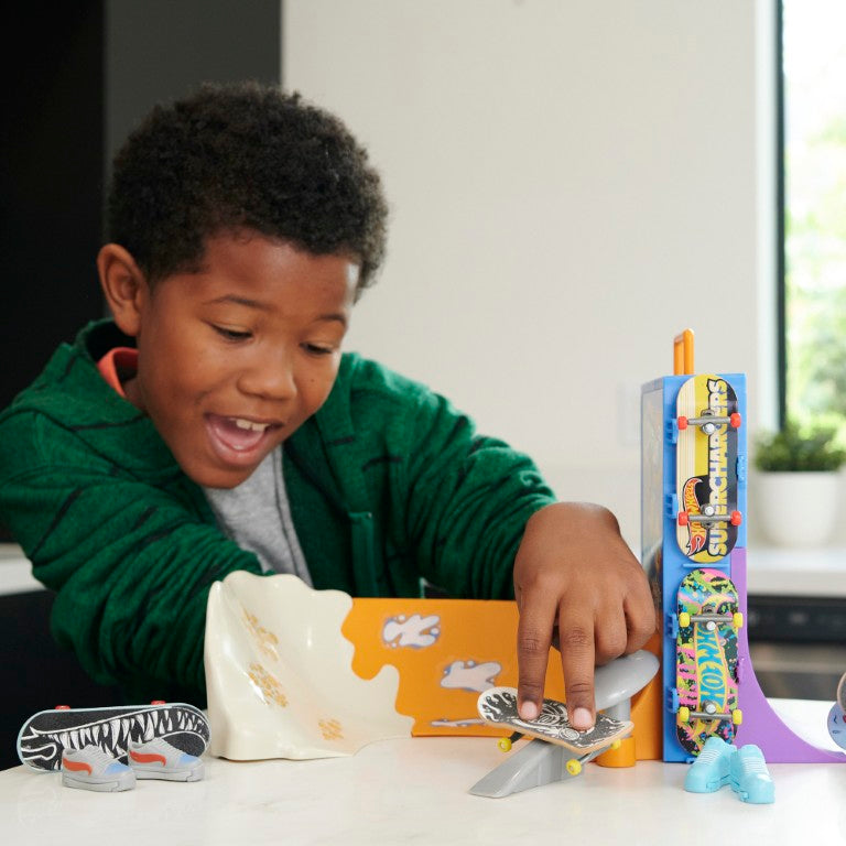 Child playing with toy skateboards and ramps on a table.