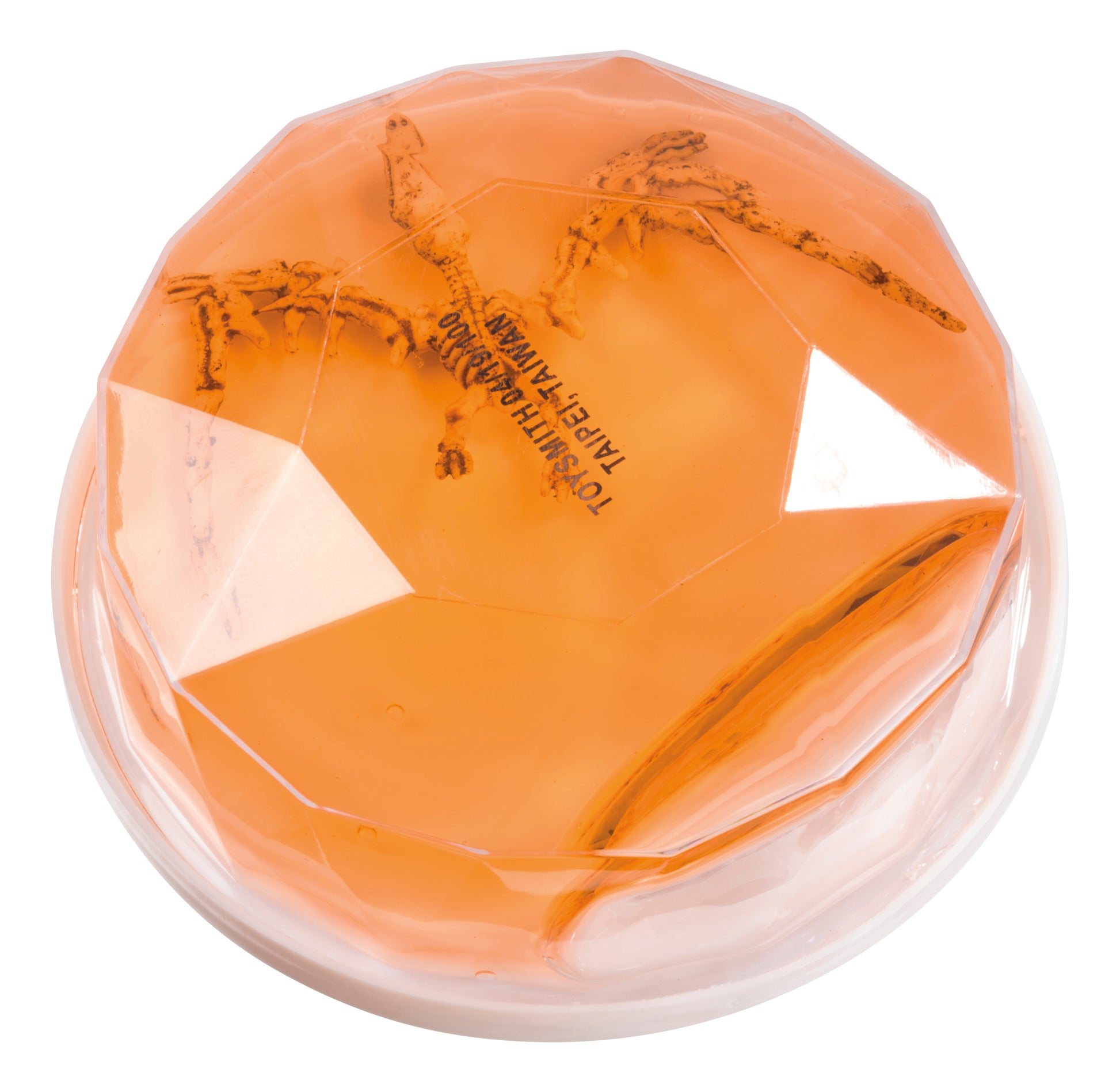 A round, faceted orange Toysmith Colorful Dinosaur Fossil Putty by Toysmith, resembling amber with a preserved insect inside, is viewed from above on a white surface.
