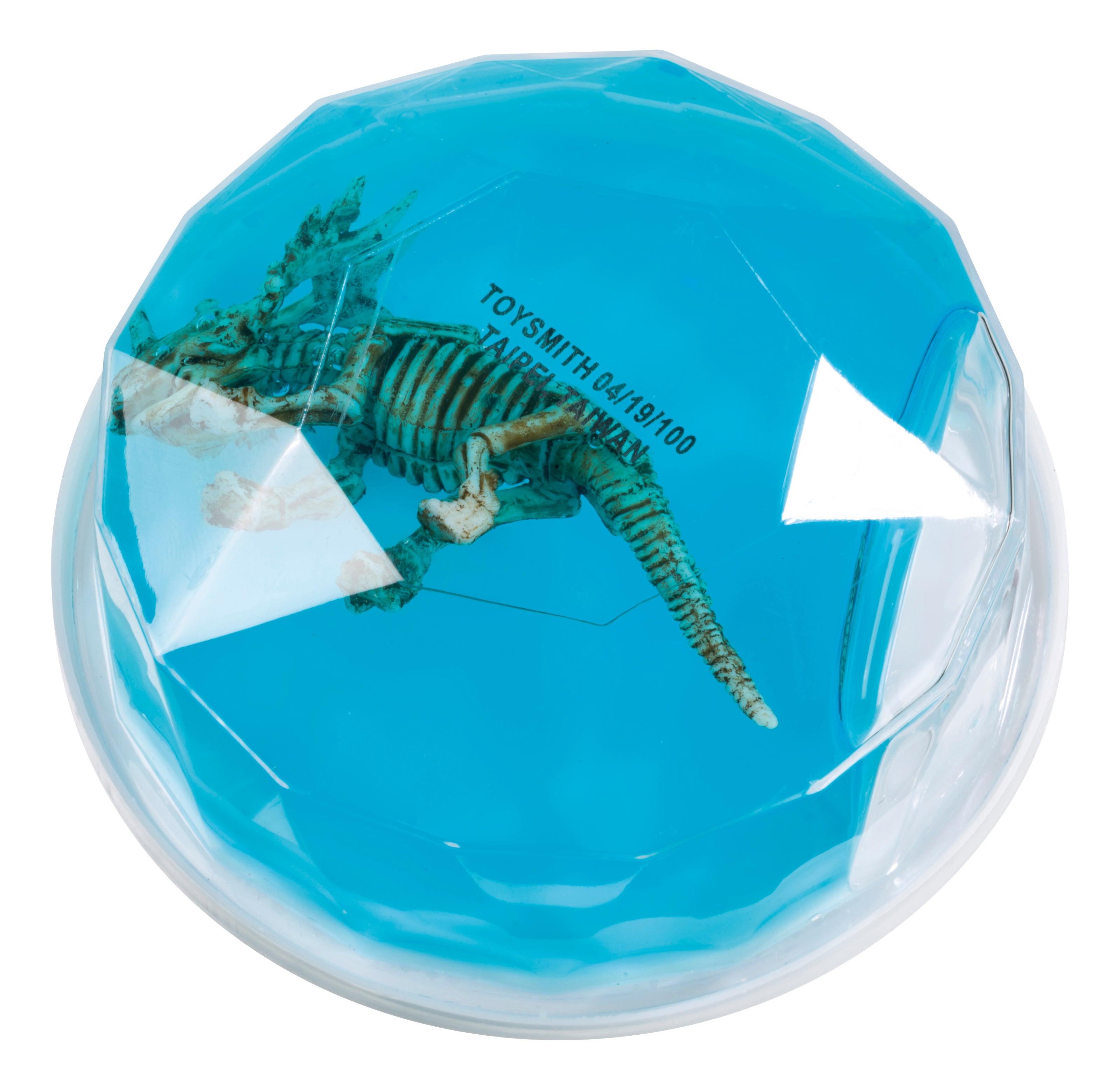 The Toysmith Colorful Dinosaur Fossil Putty features a toy dinosaur skeleton encased in clear blue putty that looks like a gemstone, with "Toysmith" visible on the surface.
