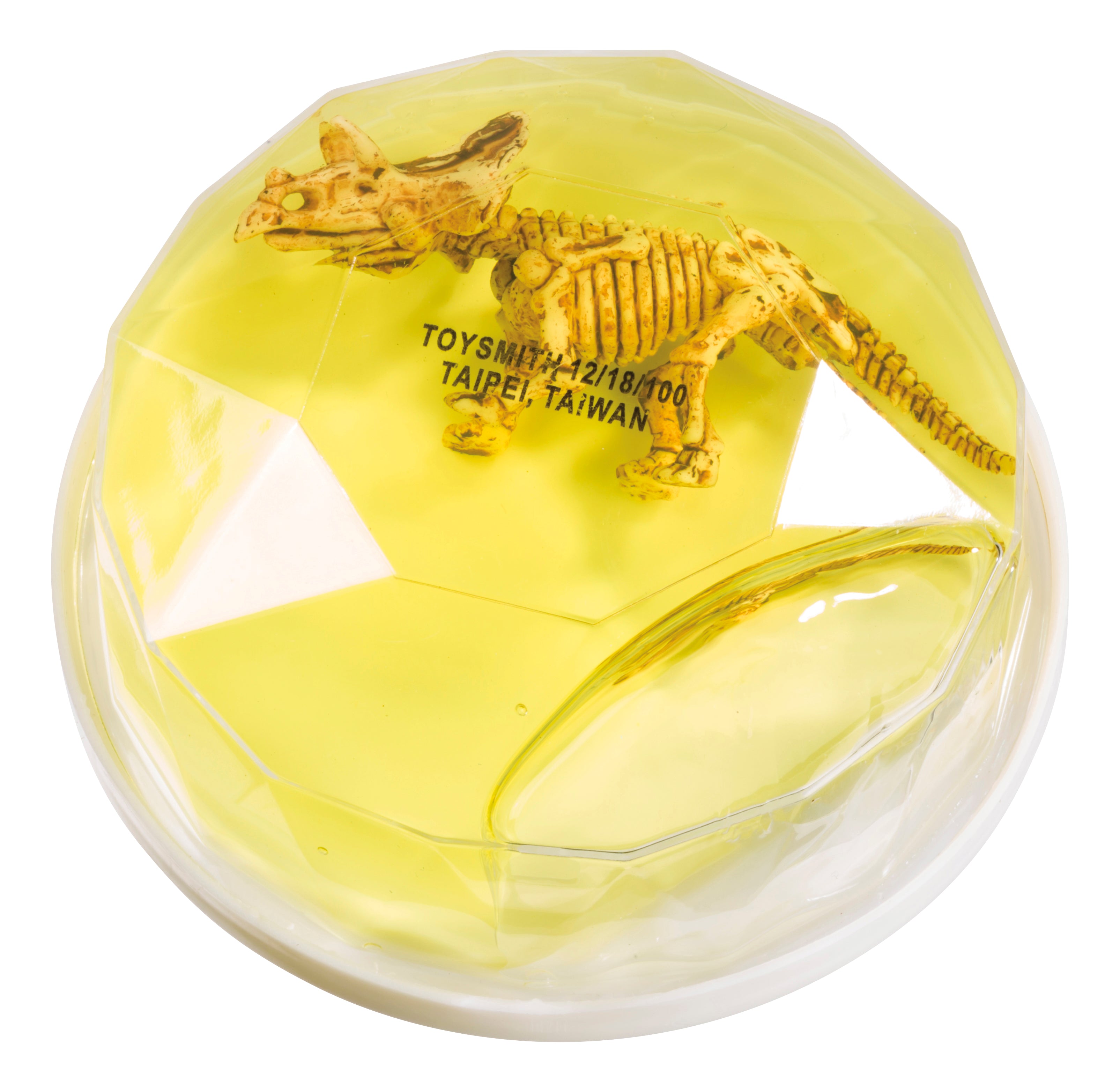 A small dinosaur skeleton from Toysmith Colorful Dinosaur Fossil Putty is encased in a yellow, translucent, gem-shaped container with "TOYSMITH TAIPEI, TAIWAN" visible inside.