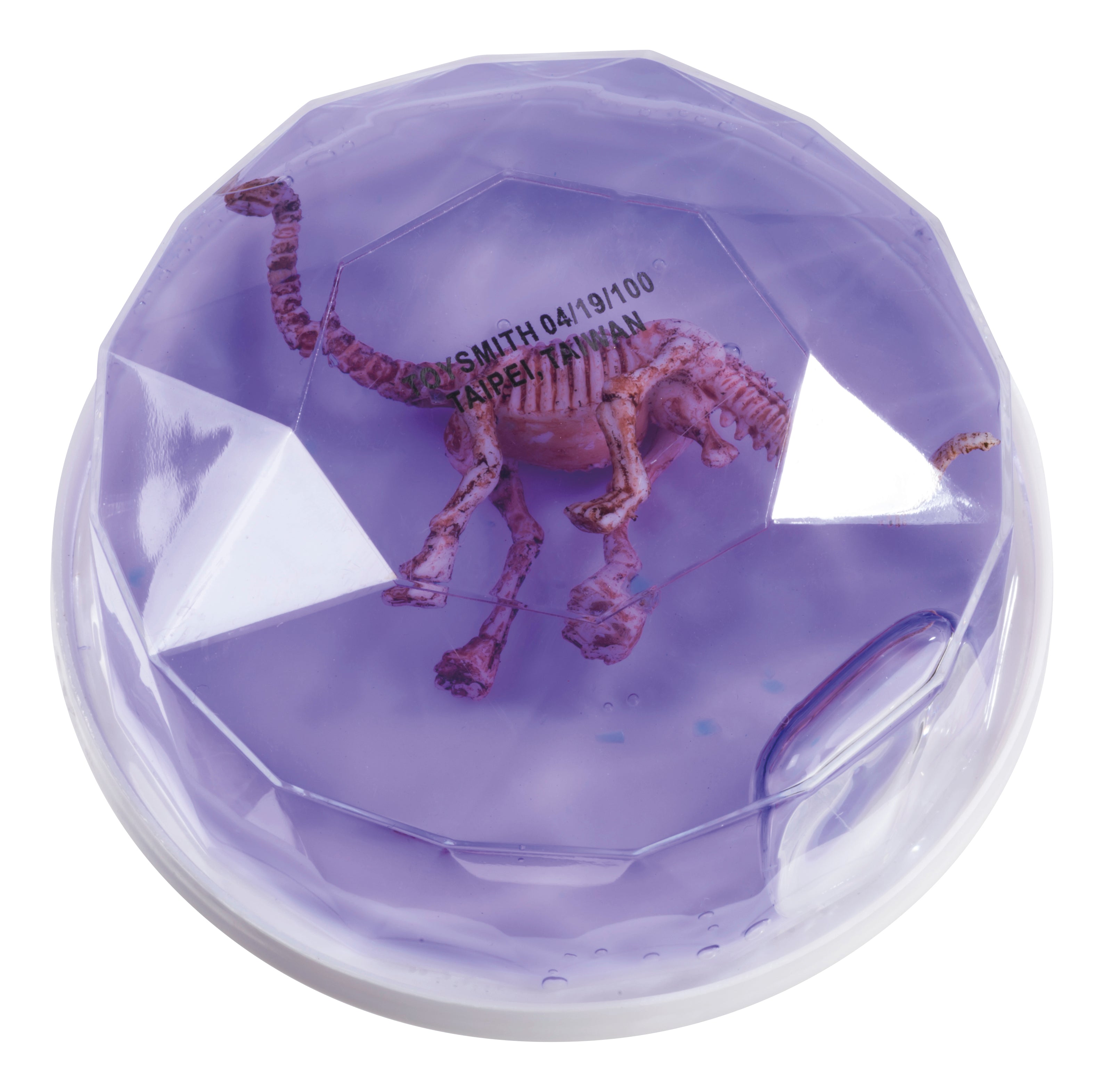 The Toysmith Colorful Dinosaur Fossil Putty by Toysmith features a small pink dinosaur skeleton encased in a faceted dome filled with clear purple gel. Some text is partly visible through the gel on the dinosaur’s rib area.