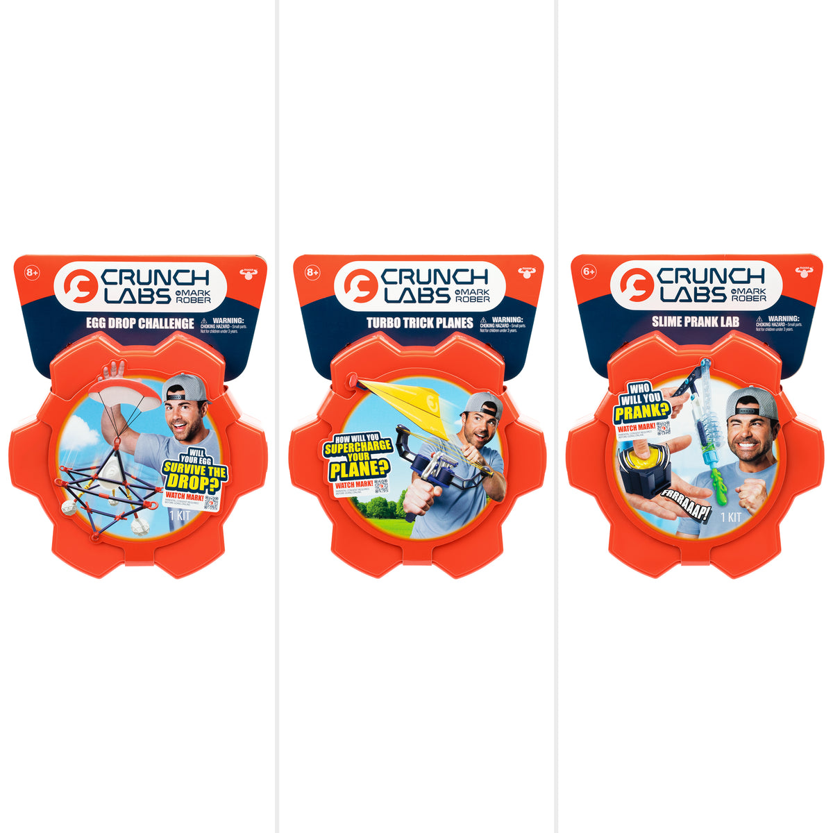 Three Crunch Lab Crunch Kits Single Pack Assortments from Moose Toys—including the Egg Drop Challenge, Turbo Trick Planes, and Slime Prank Lab—each arrive in bright orange gear-shaped packaging featuring kid-friendly graphics and a smiling Mark Rober on the front.