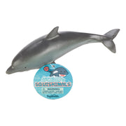 A realistic gray dolphin Toysmith Sea Life Squishimal with a round blue "Ocean Squishimals by Toysmith" tag, designed for sensory play and recommended for ages 3 and up.