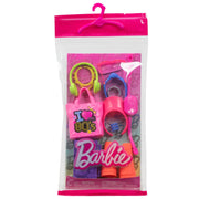 The Mattel Barbie Fashion Storytelling Pack includes 80s-themed fashion accessories—a pink tote bag, green and yellow headset, pink sunglasses, cup, and Barbie logo—packaged in a clear plastic bag with a pink hanger for creative play.