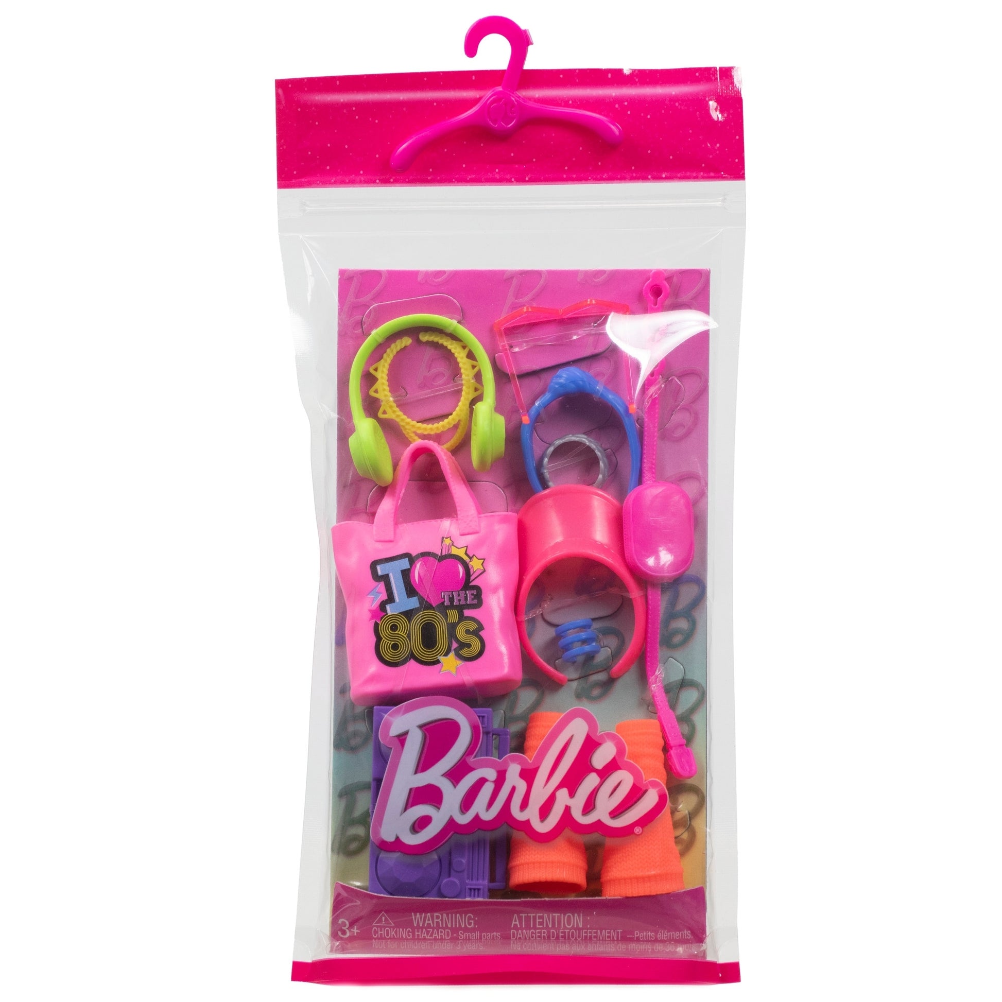 The Mattel Barbie Fashion Storytelling Pack includes 80s-themed fashion accessories—a pink tote bag, green and yellow headset, pink sunglasses, cup, and Barbie logo—packaged in a clear plastic bag with a pink hanger for creative play.