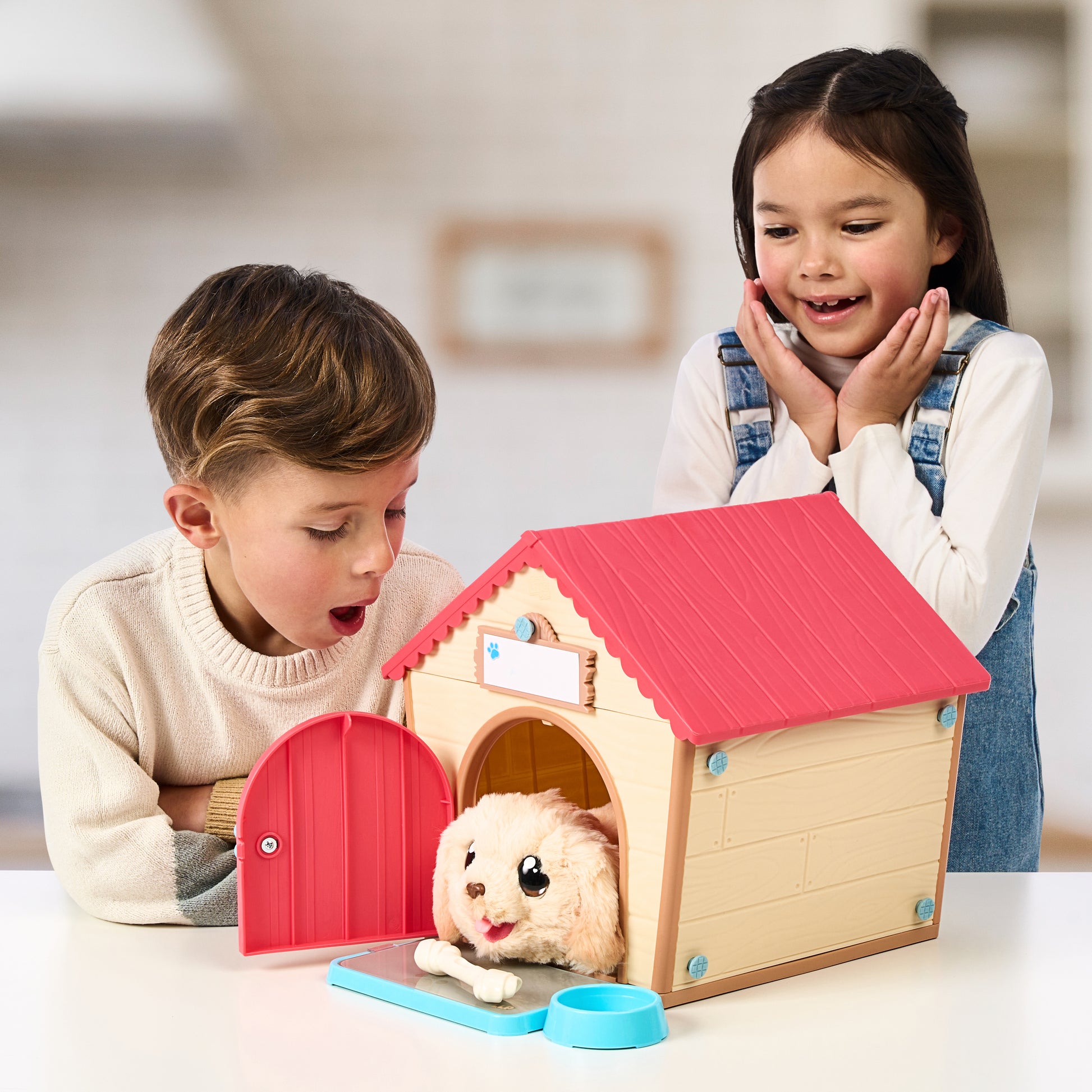 Two children playing with a toy dog house and plush dog inside.