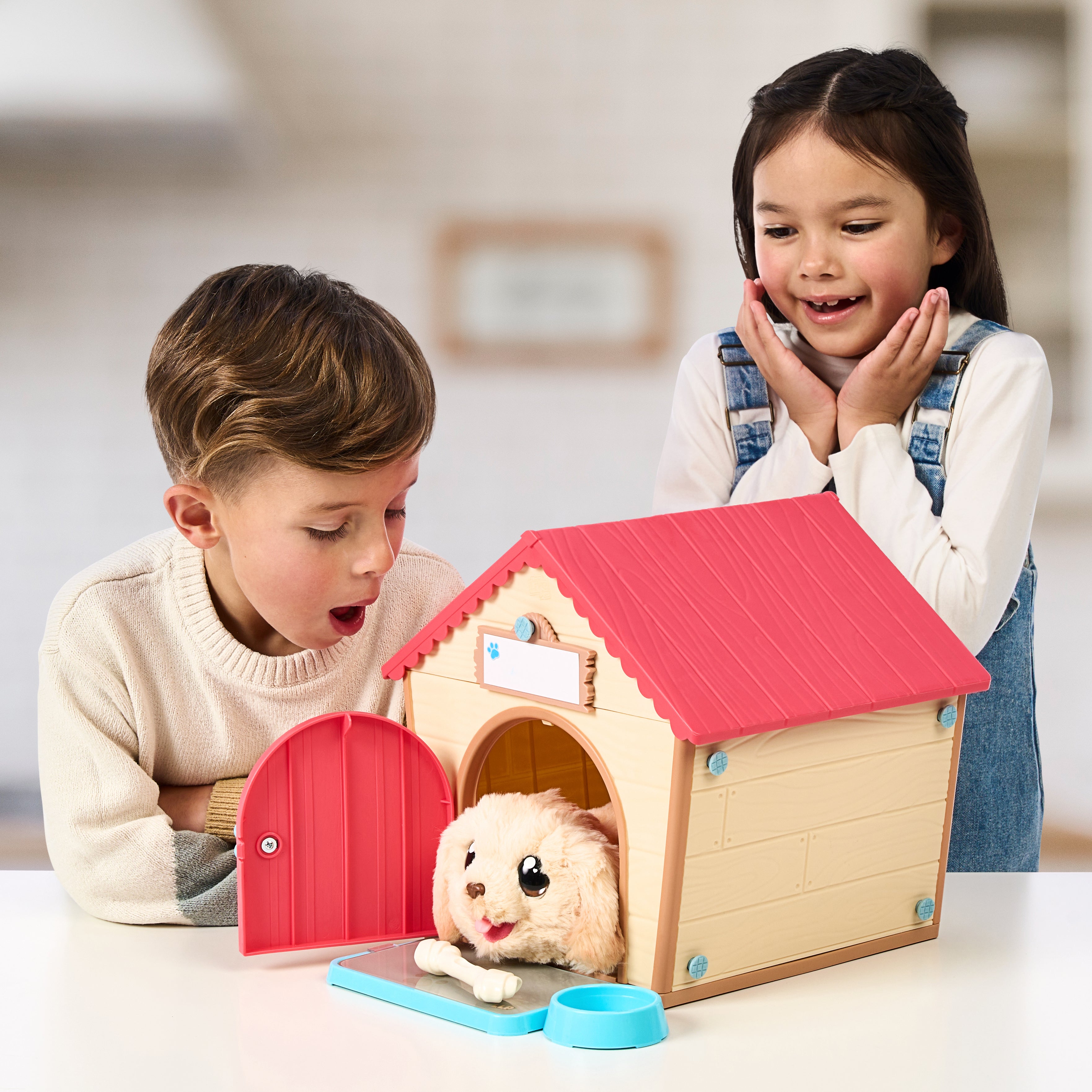 Two children playing with a toy dog house and plush dog inside.