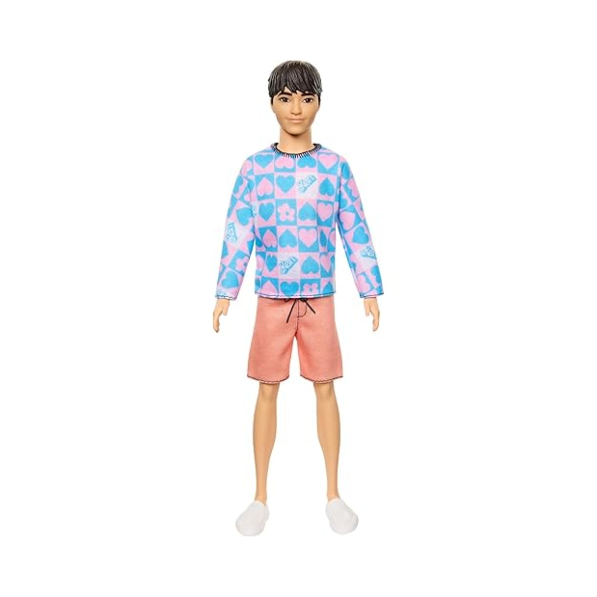 The Mattel Barbie Ken Fashionistas Doll features short dark hair, a blue long-sleeve shirt with pink heart and star patterns, pink drawstring shorts, and white slip-on shoes, shown against a plain white background.