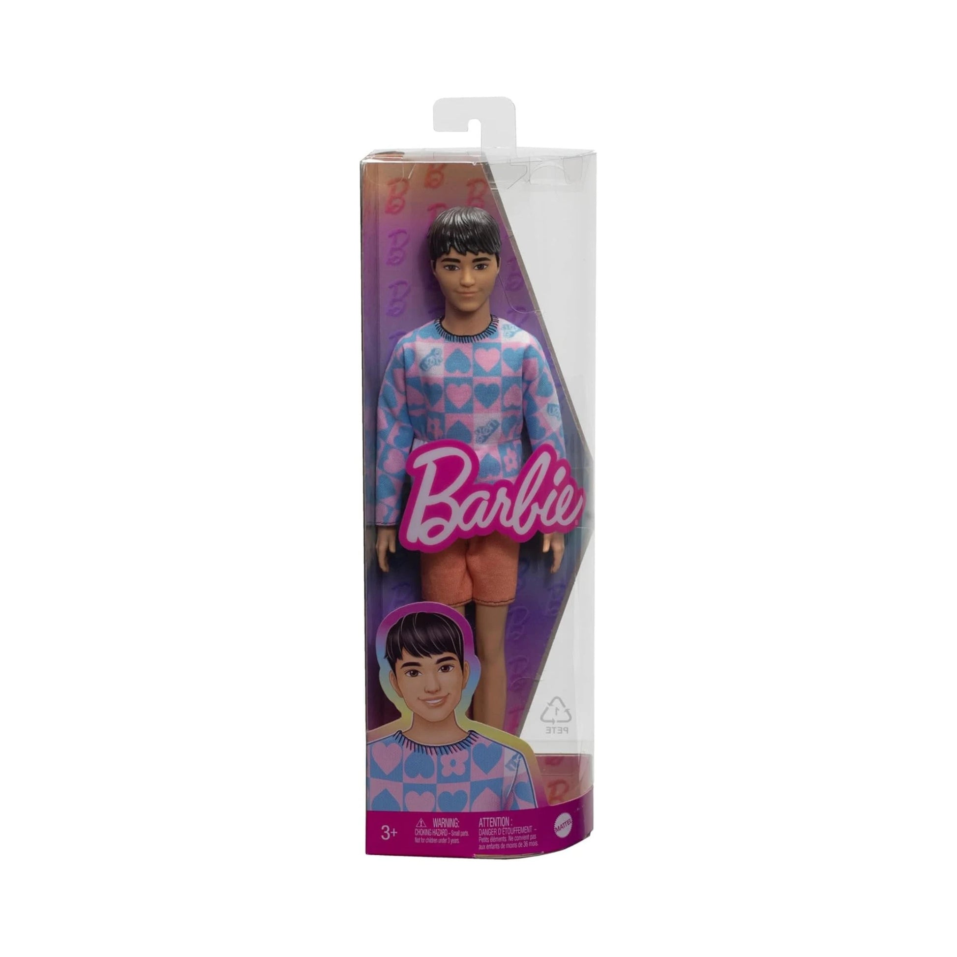 The Mattel Barbie Ken Fashionistas Doll comes in a box featuring the Barbie logo and an illustrated portrait of Ken. The doll wears a light blue and pink patterned sweater paired with pink shorts.
