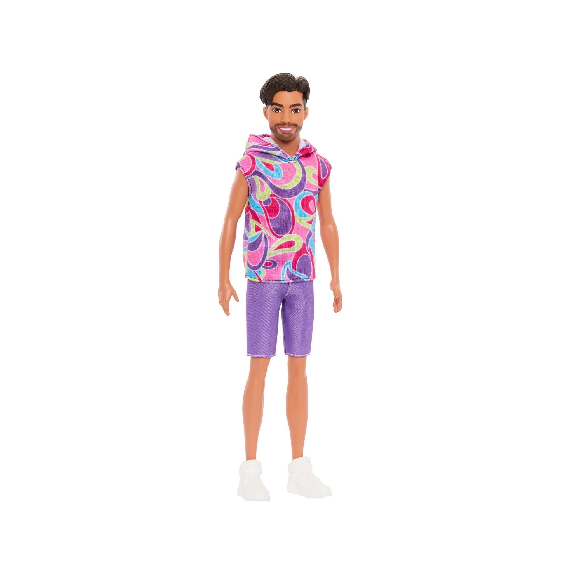 The Mattel Barbie Ken Fashionistas Doll features dark hair and a beard, dressed in a colorful sleeveless hoodie with pink, blue, and purple patterns, purple shorts, and white sneakers, posed confidently against a white background.