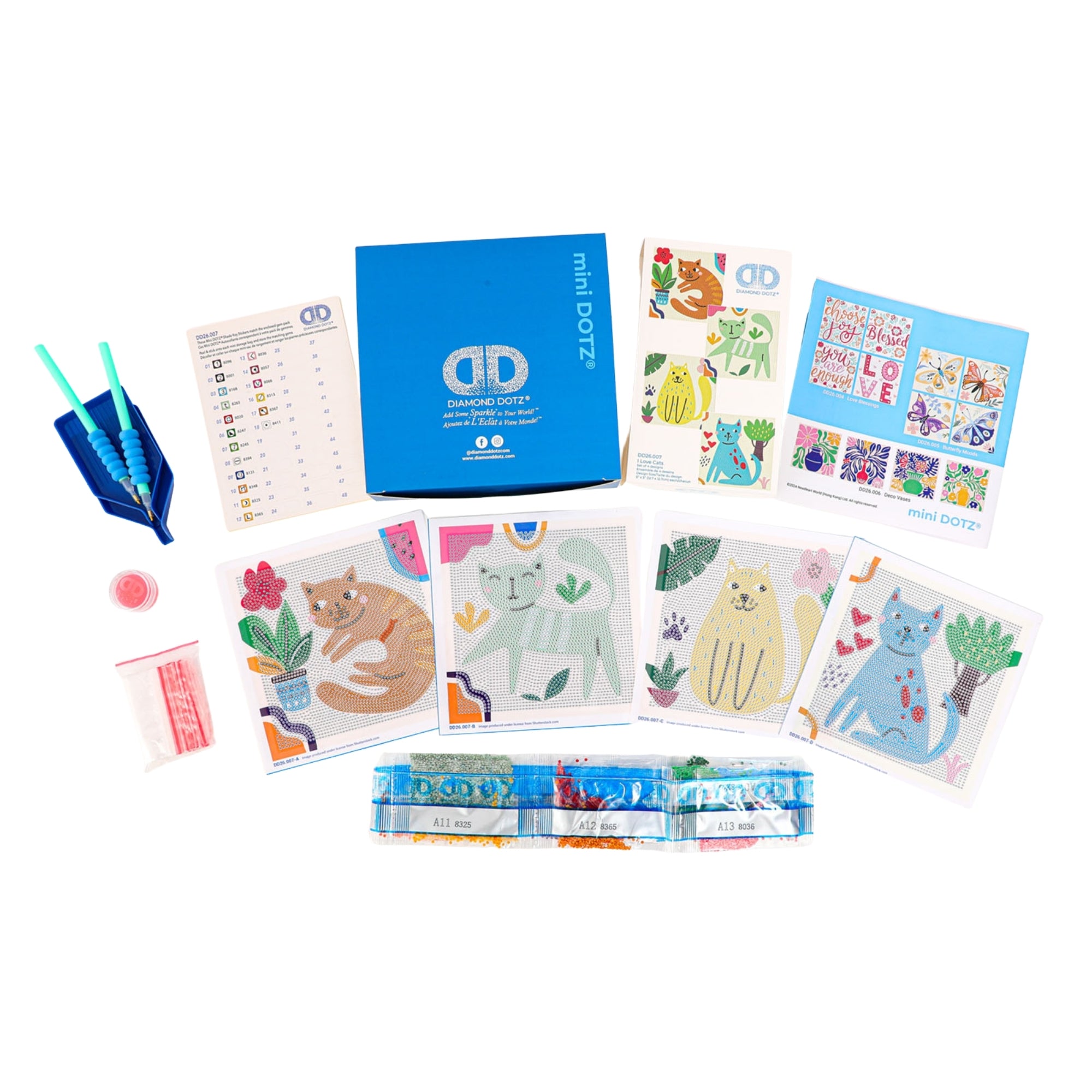 Diamond Dotz Mini Dotz kit includes a blue box, gem applicator tools, colored beads, instructions, and several cat-themed art cards with colorful, whimsical cats and plants.