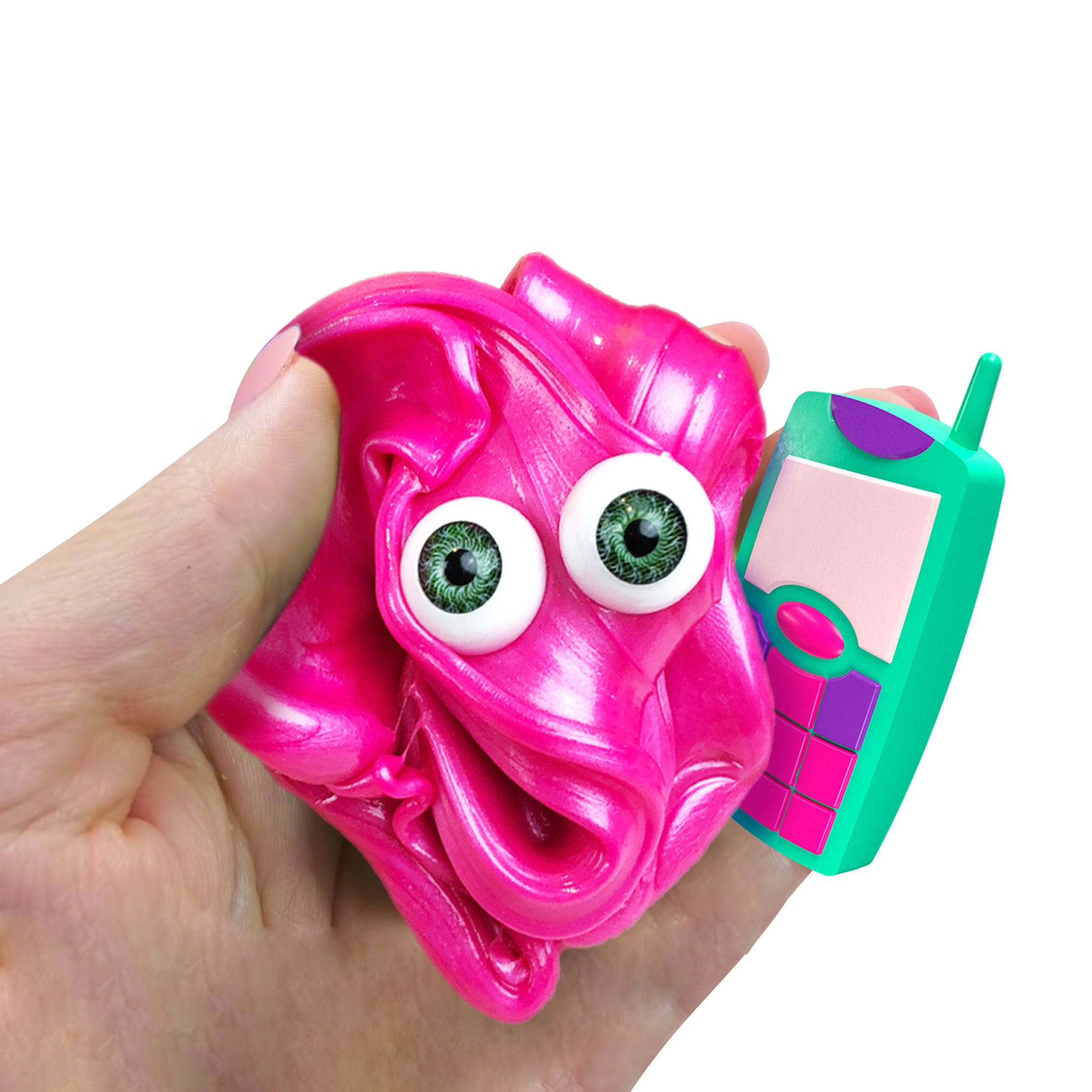 A hand holds a shiny pink Doctor Squish Putty Buddies Asst. slime with googly eyes, next to a colorful toy cellphone with large buttons, both set against a plain white background.