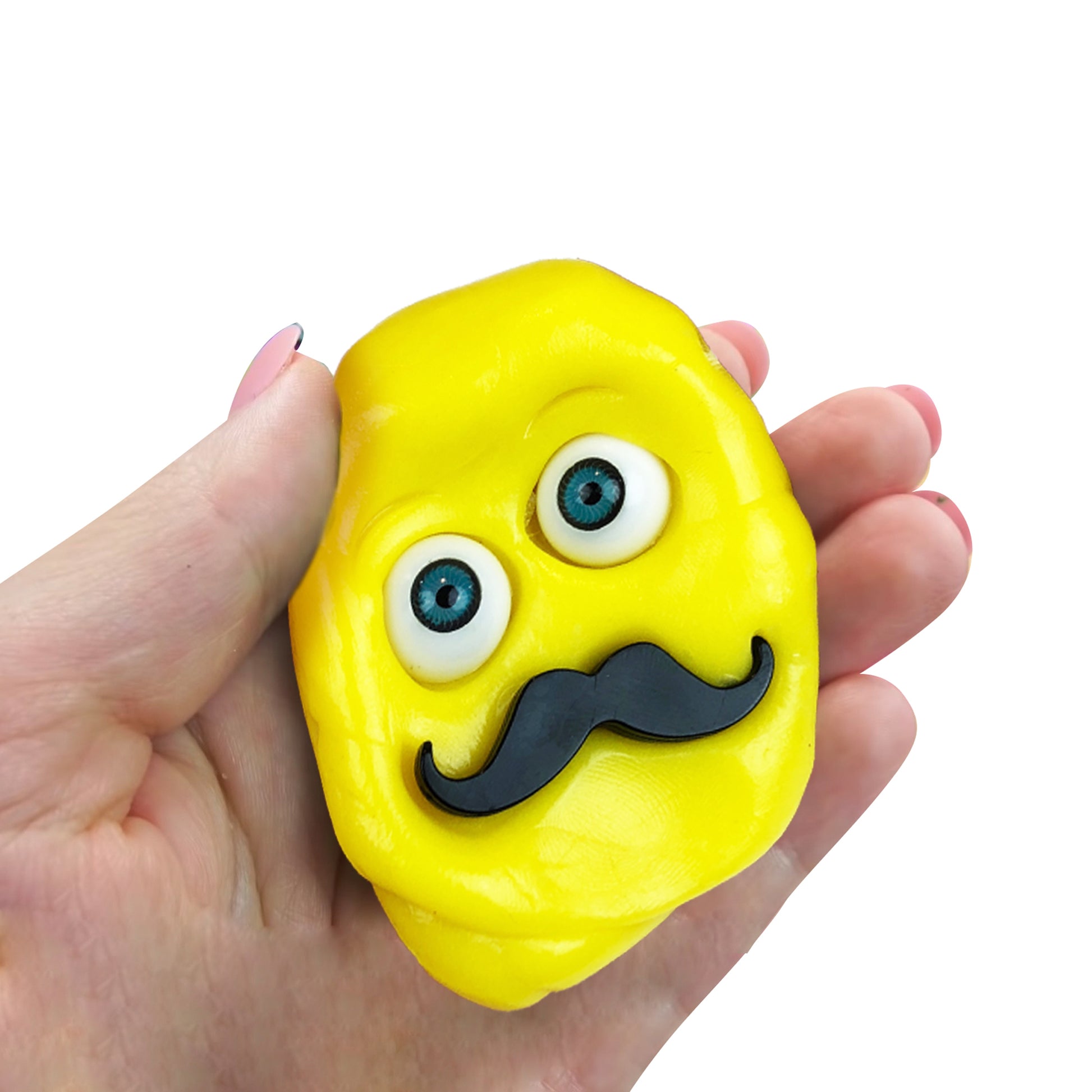 A hand holds a yellow squishy character with big blue cartoon eyes and a black mustache from the Doctor Squish Putty Buddies Asst. 21ct CDU, shown against a white background.