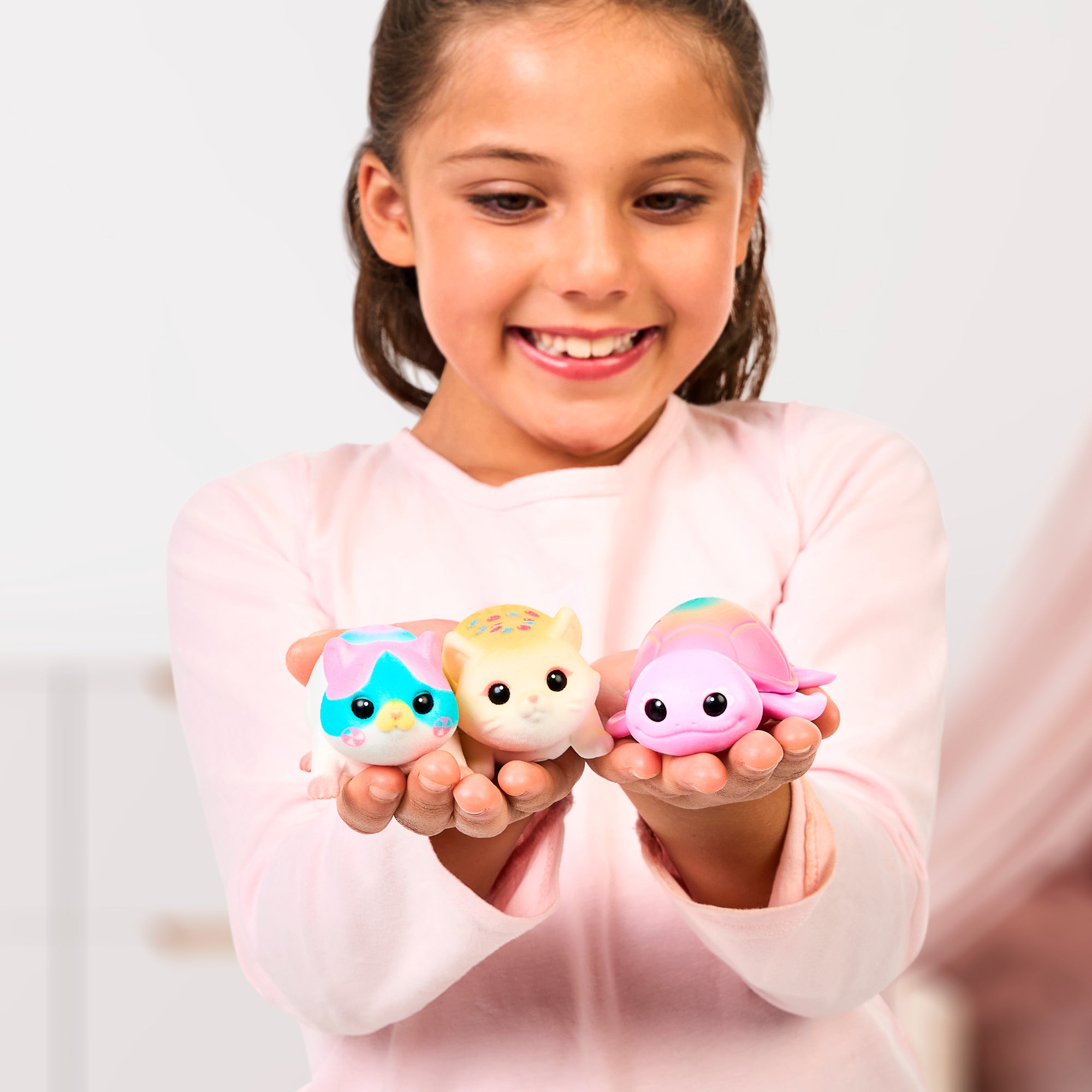 Girl holding three Little Live Pets NeeDees against a plain background