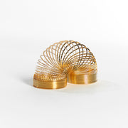 The Neato! Metal Magic Spring, a classic gold toy, is displayed in an arched shape against a white background.