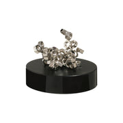 The Project Blueprint Magnetic Sculpture features silver metal nuts stacked abstractly on a round black base, creating a striking desk accessory that stands out against a white background.