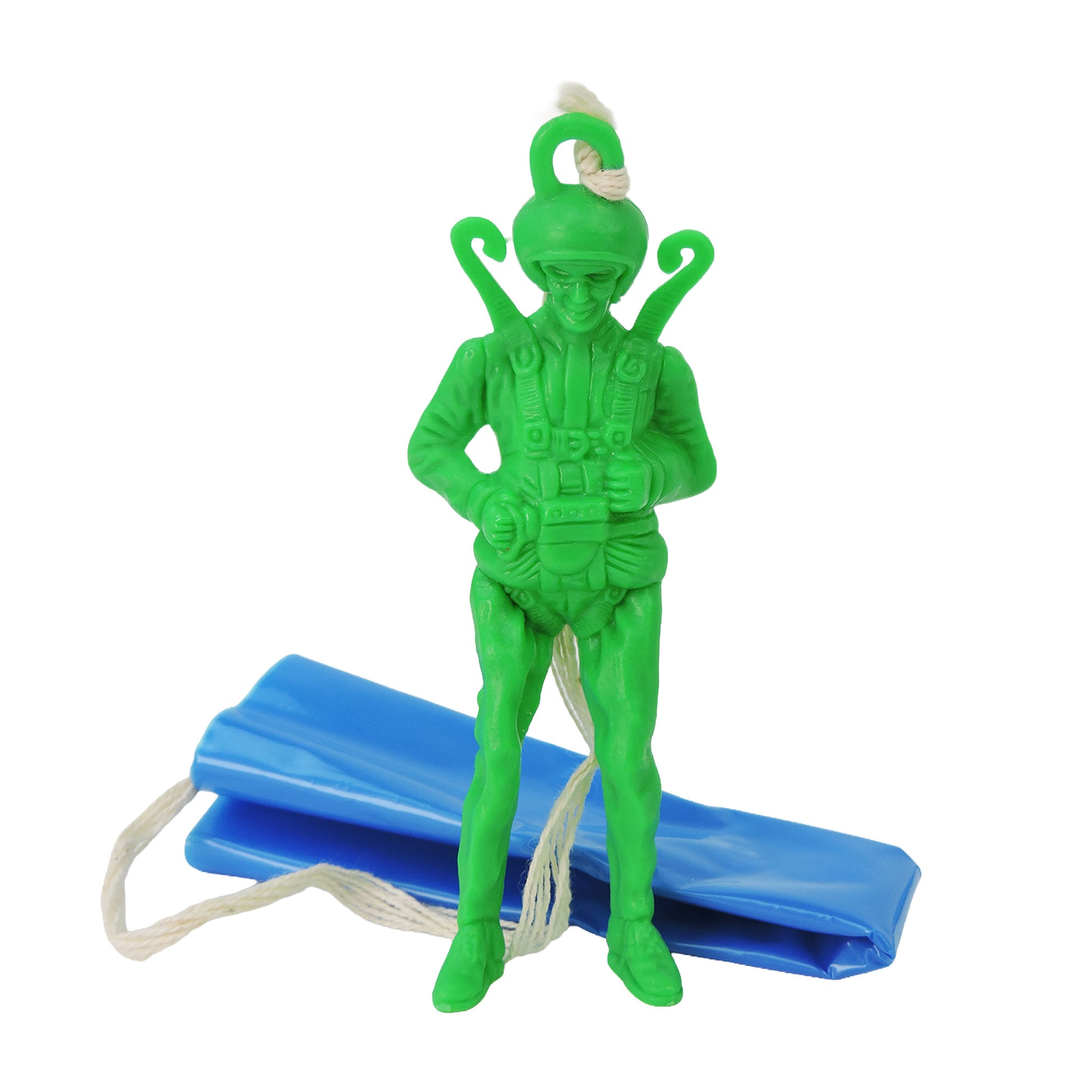 The Toysmith Giant Parachuter Figure, a green plastic toy soldier with helmet and parachute gear, stands before a folded blue plastic parachute with attached white string.