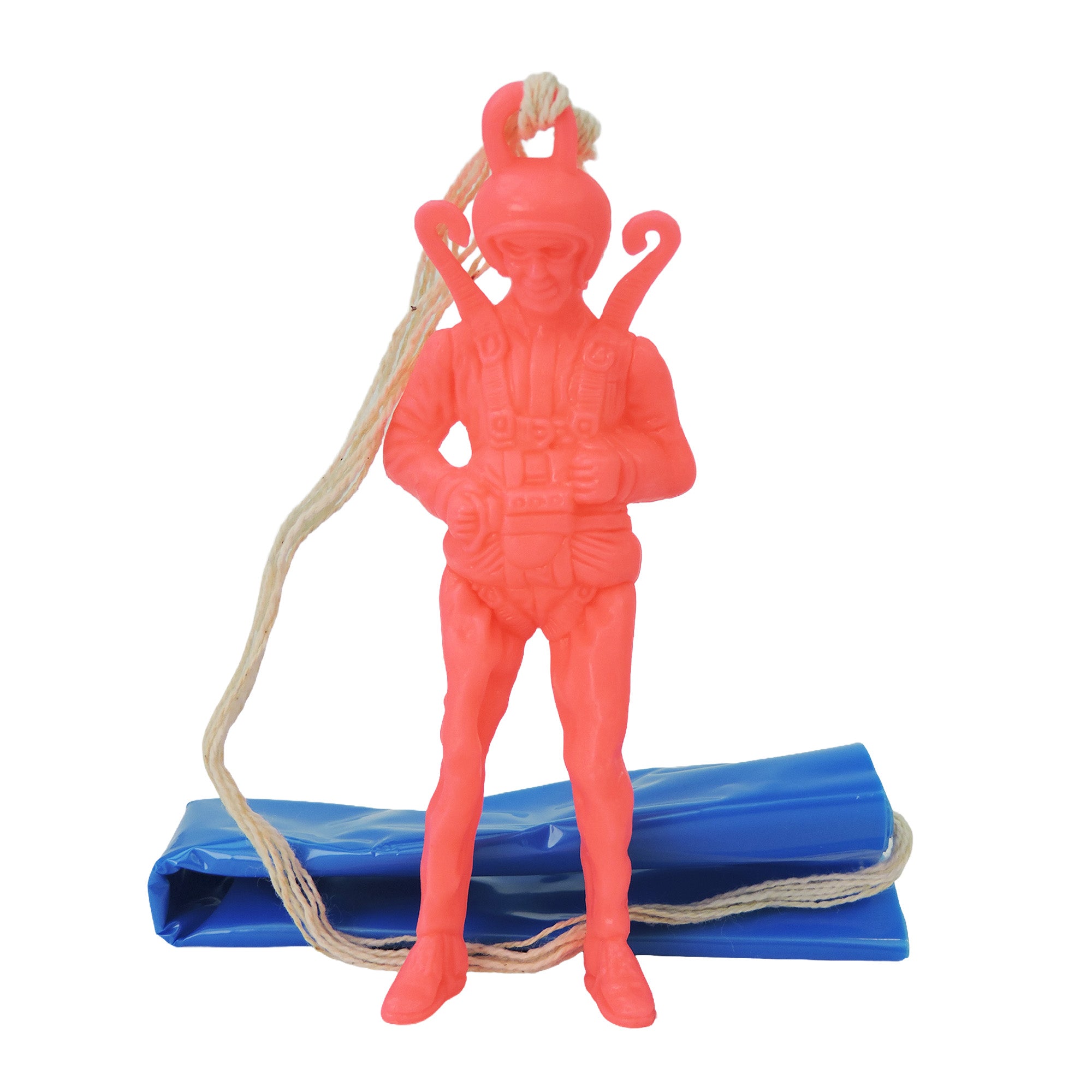The Toysmith Giant Parachuter Figure by Toysmith is a pink plastic toy with a string on its back, standing before a folded blue parachute.