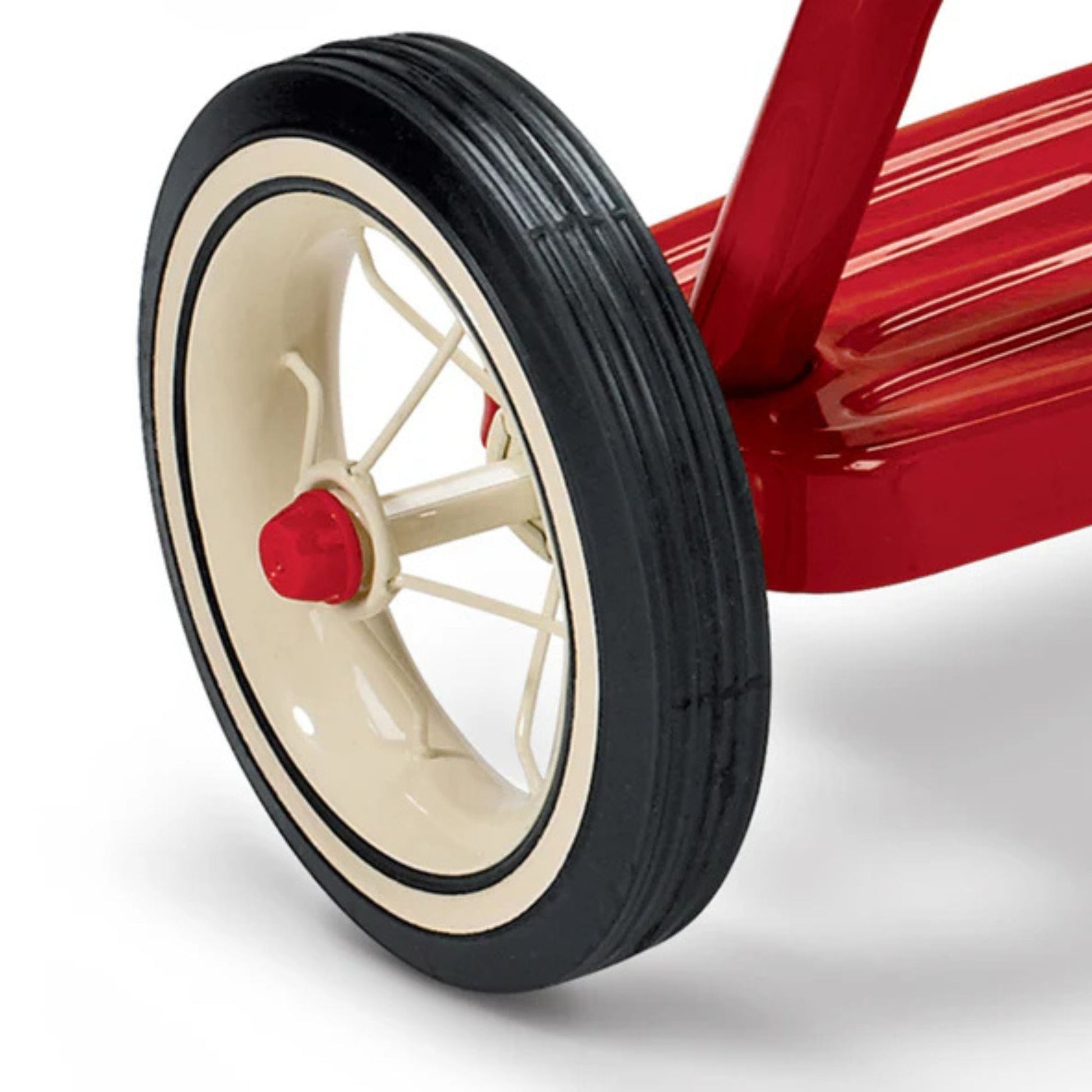 Close-up of the Radio Flyer Classic Red Dual Deck Tricycle’s rear wheel, featuring a black tire, cream spokes, red hub, and red metal frame with footrest. Brand: Radio Flyer.