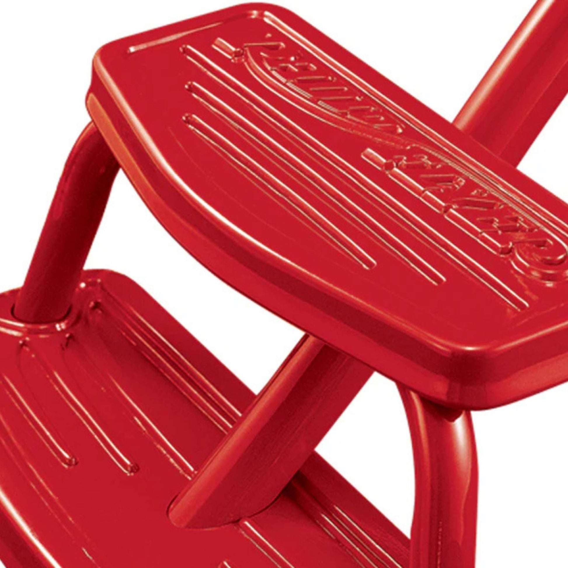 Close-up of two bright red metal steps with textured surfaces and embossed text on the Radio Flyer Classic Red Dual Deck Tricycle by Radio Flyer.