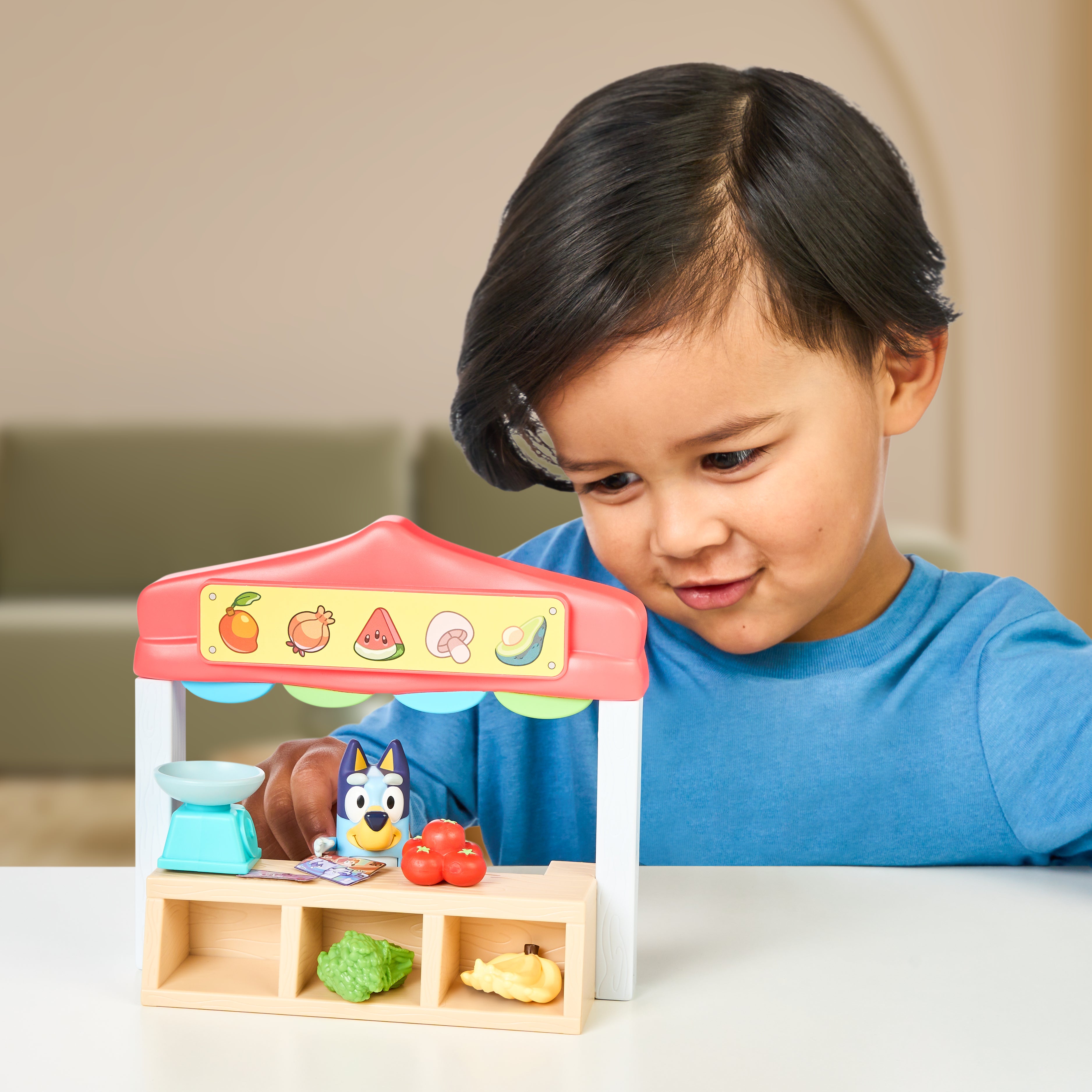 Child playing with a Bluey toy fruit stand at a table