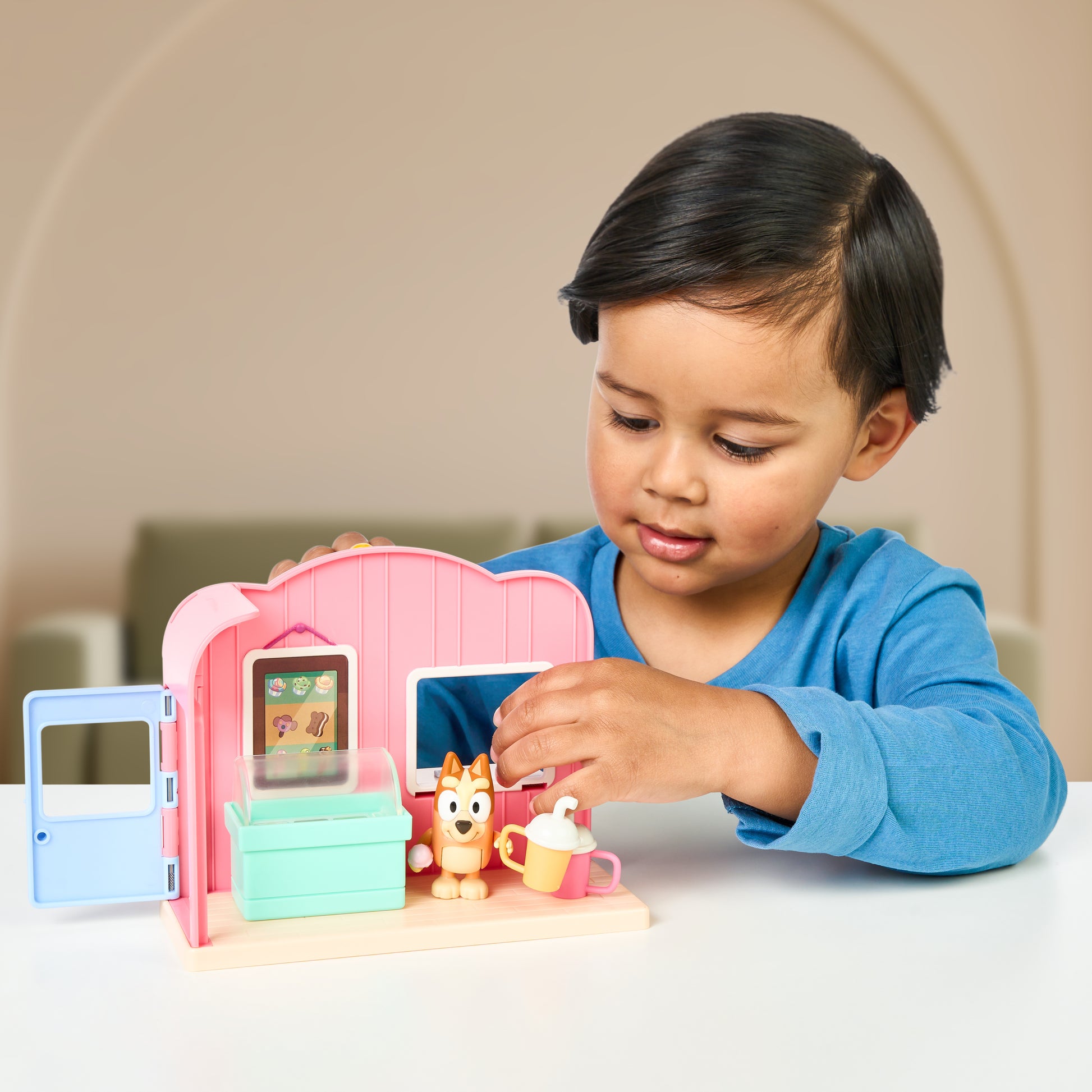 Child playing with a Bluey toy playset on a table