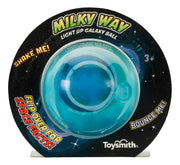 A packaged Toysmith Light-Up Galaxy Ball, a glowing space-themed toy with a blue center sphere. The starry packaging displays “Shake Me!”, “Bounce Me!”, and “Flip Over for Space Facts!” Brand: Toysmith.