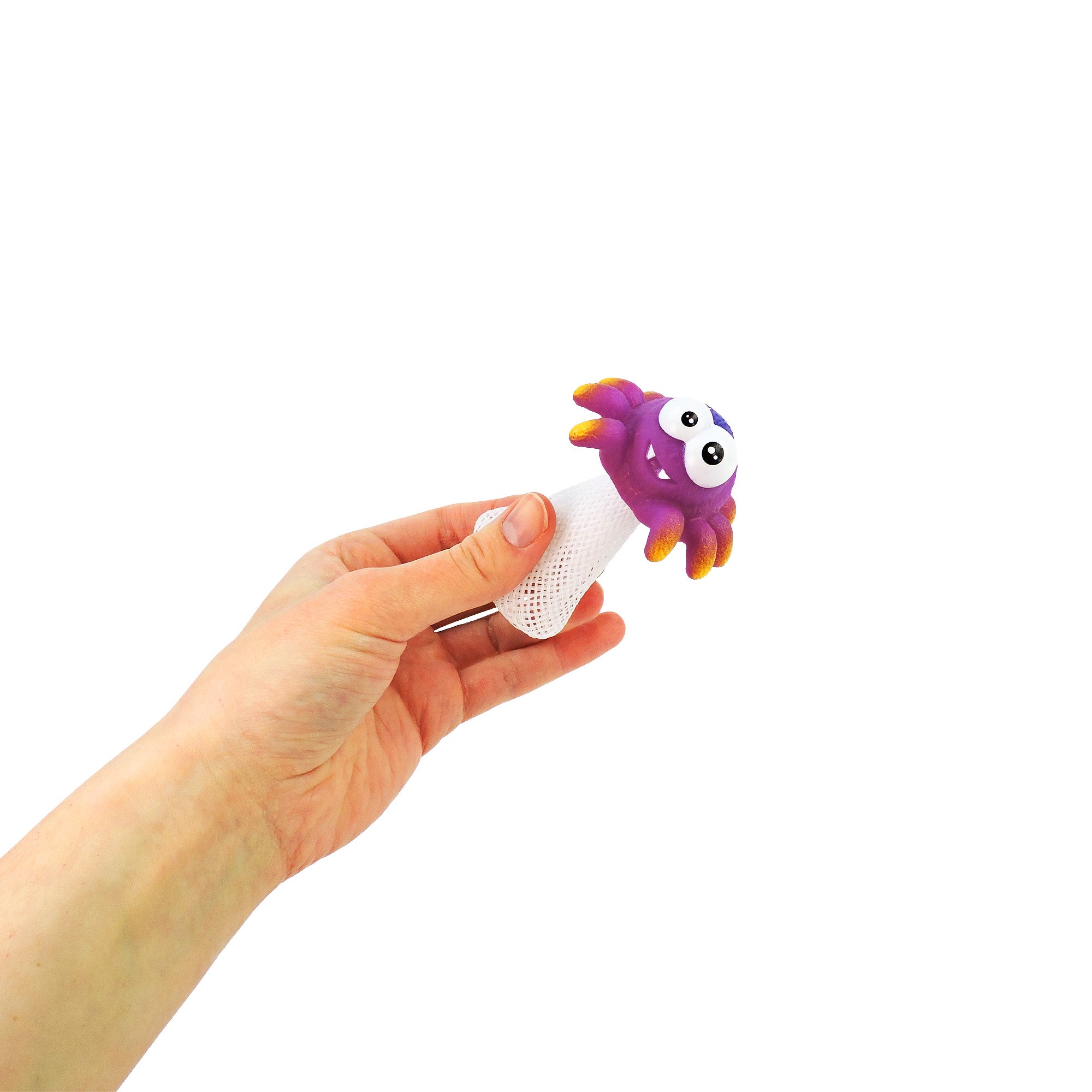 A hand holds the Toysmith Jumping Spider—a playful prank toy by Toysmith with a smiling purple monster face, orange spikes, and a white mesh base—shown popping up against a plain white background.