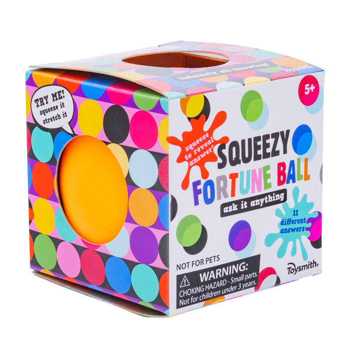 A colorful, polka-dotted box with a round opening displays an orange Toysmith Squeezy Fortune Ball fidget toy. The packaging reads "Squeezy Fortune Ball," "ask it anything," is for ages 5+, and features visible warning labels.