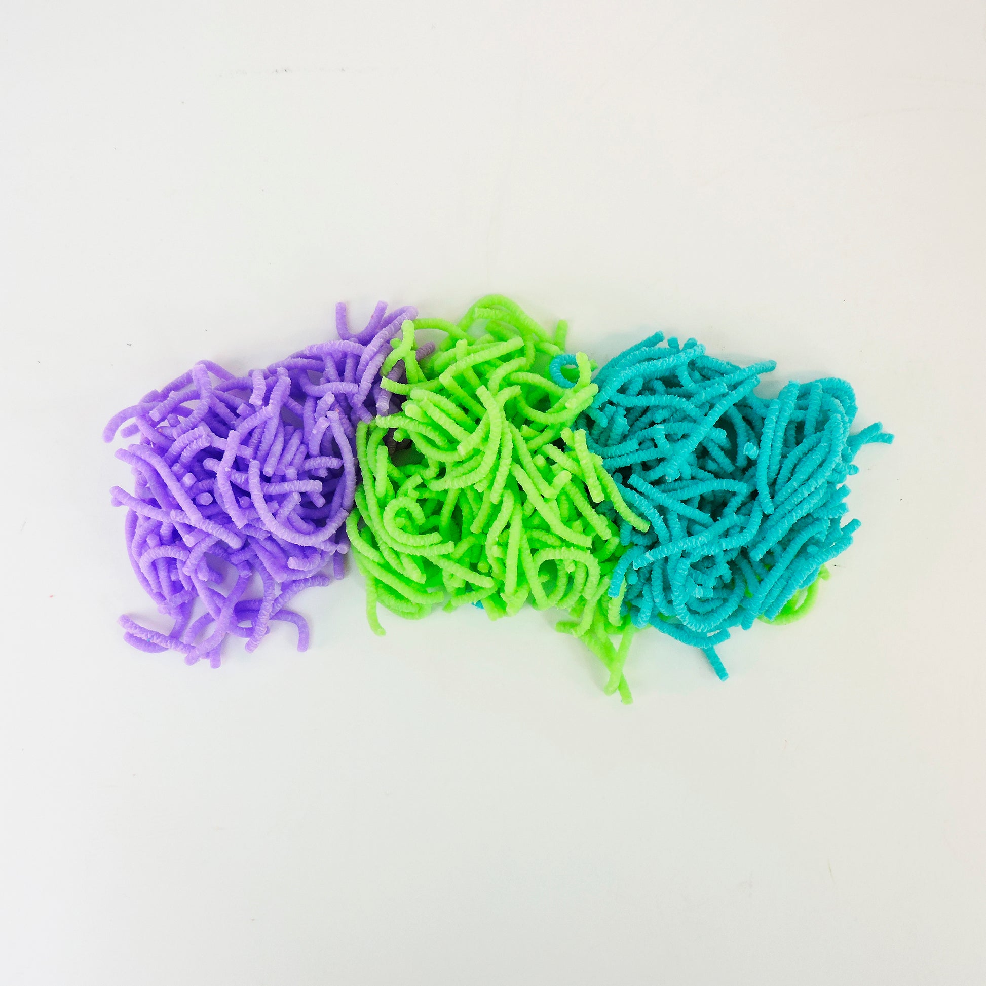 Three piles of Sensory Lab Wrigglin Worms in purple, green, and blue are placed side by side on a plain white background.