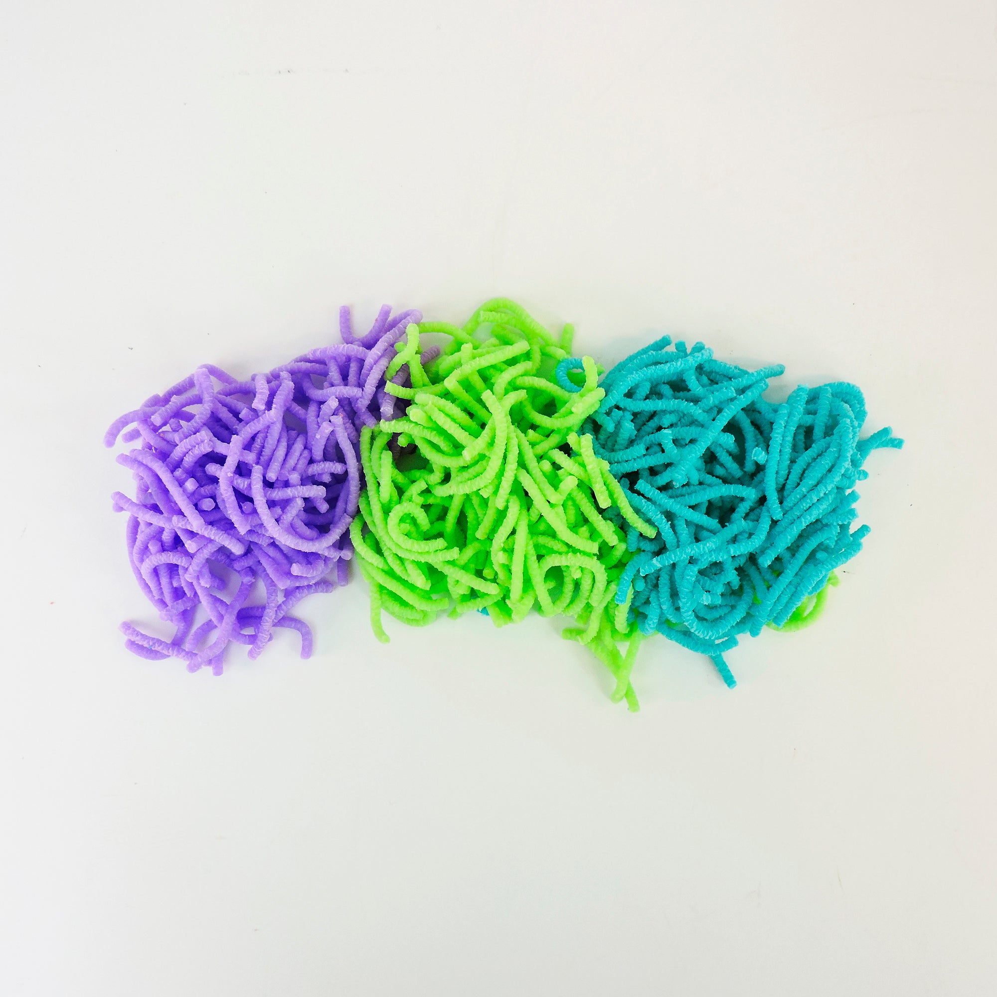 Three piles of Sensory Lab Wrigglin Worms in purple, green, and blue are placed side by side on a plain white background.