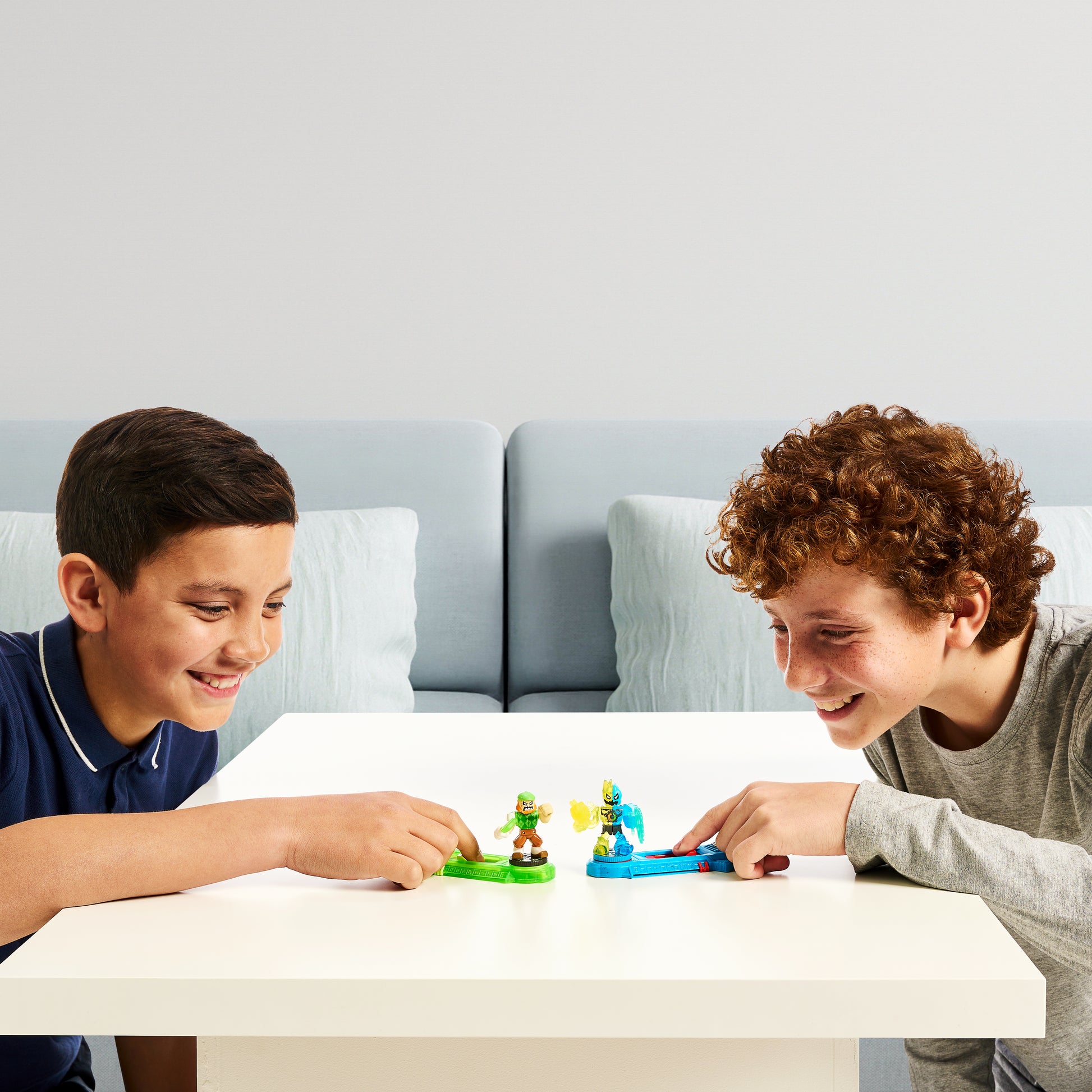 Two children playing with toy figures on a table in a living room setting.