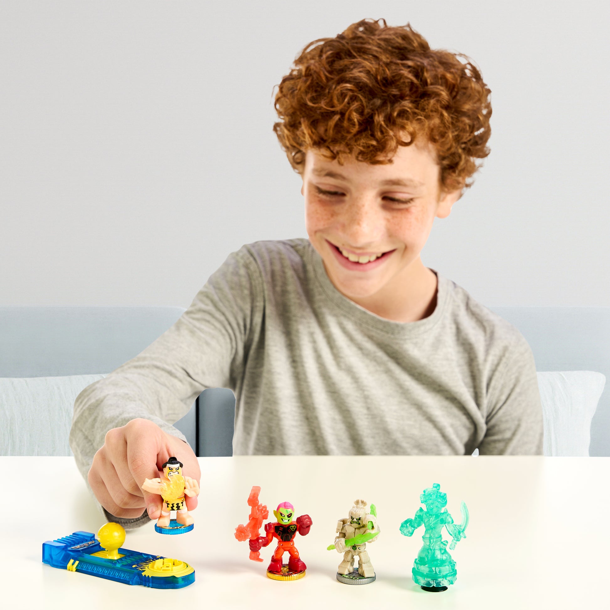 Child playing with toy figures on a table against a plain background