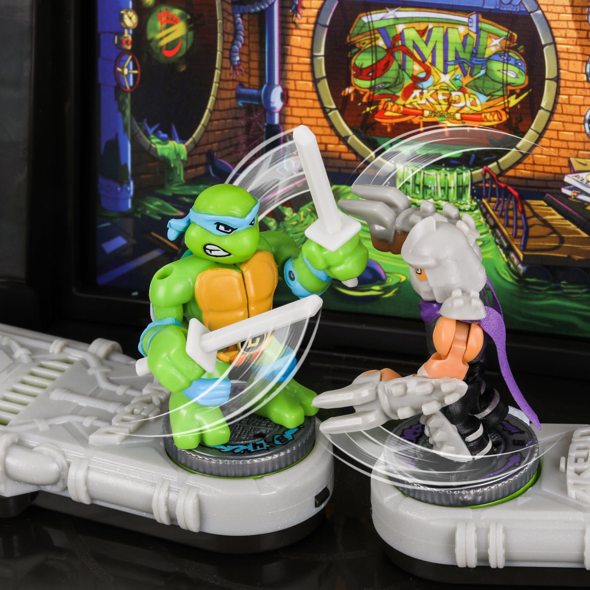 Two toy figures in front of a Teenage Mutant Ninja Turtles arcade machine.