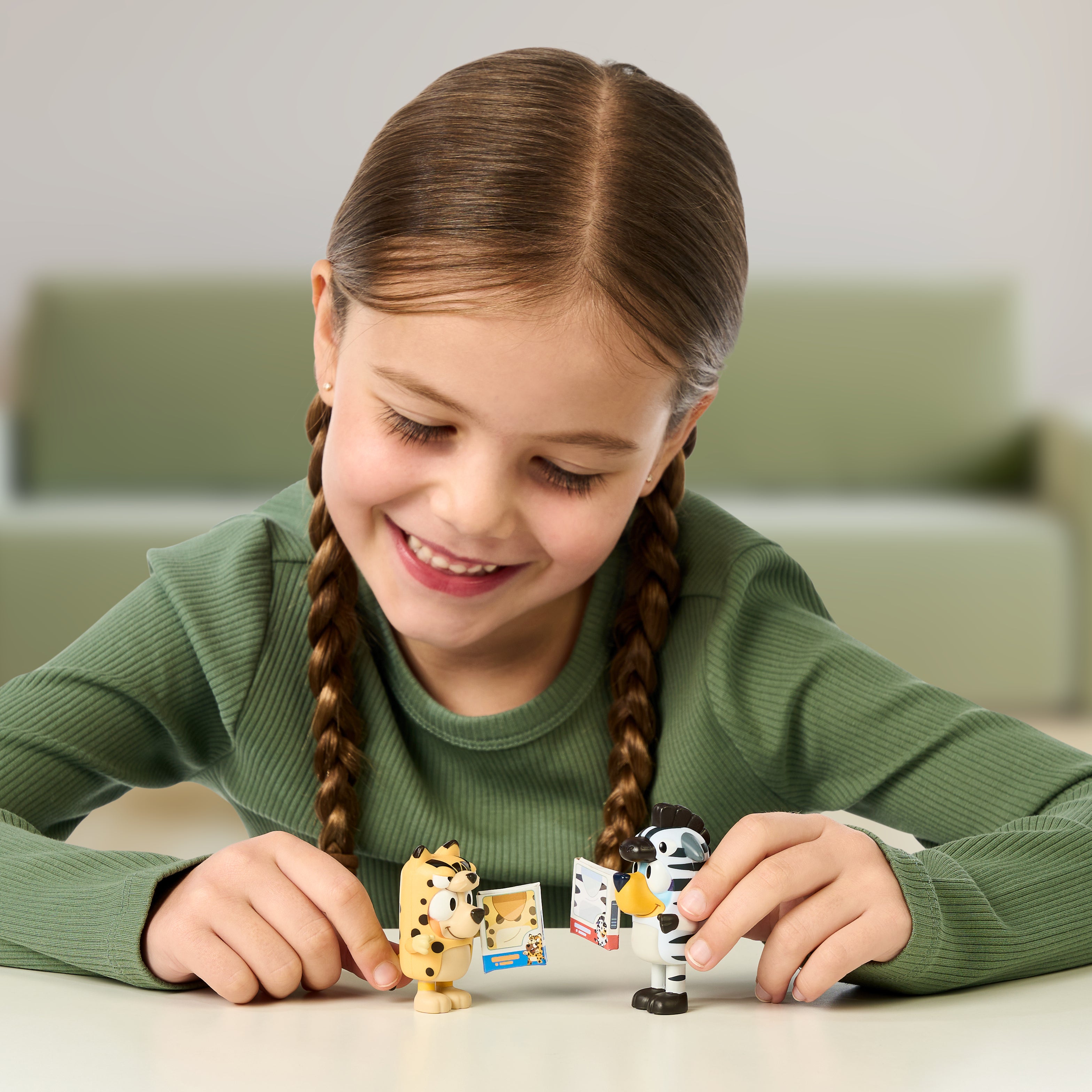 Young girl playing with Bluey figurines on a table