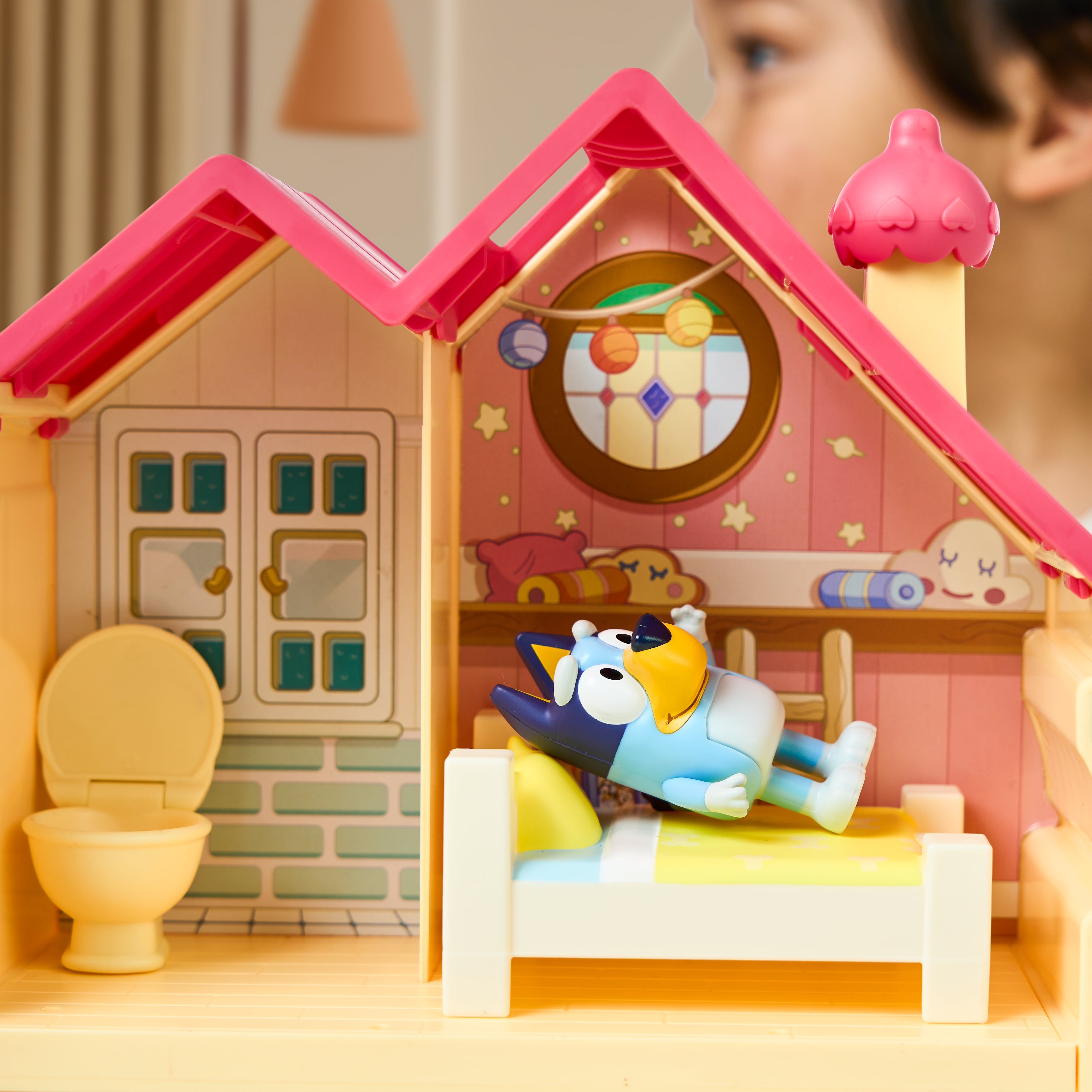Toy house with a character inside, blurred child in the background