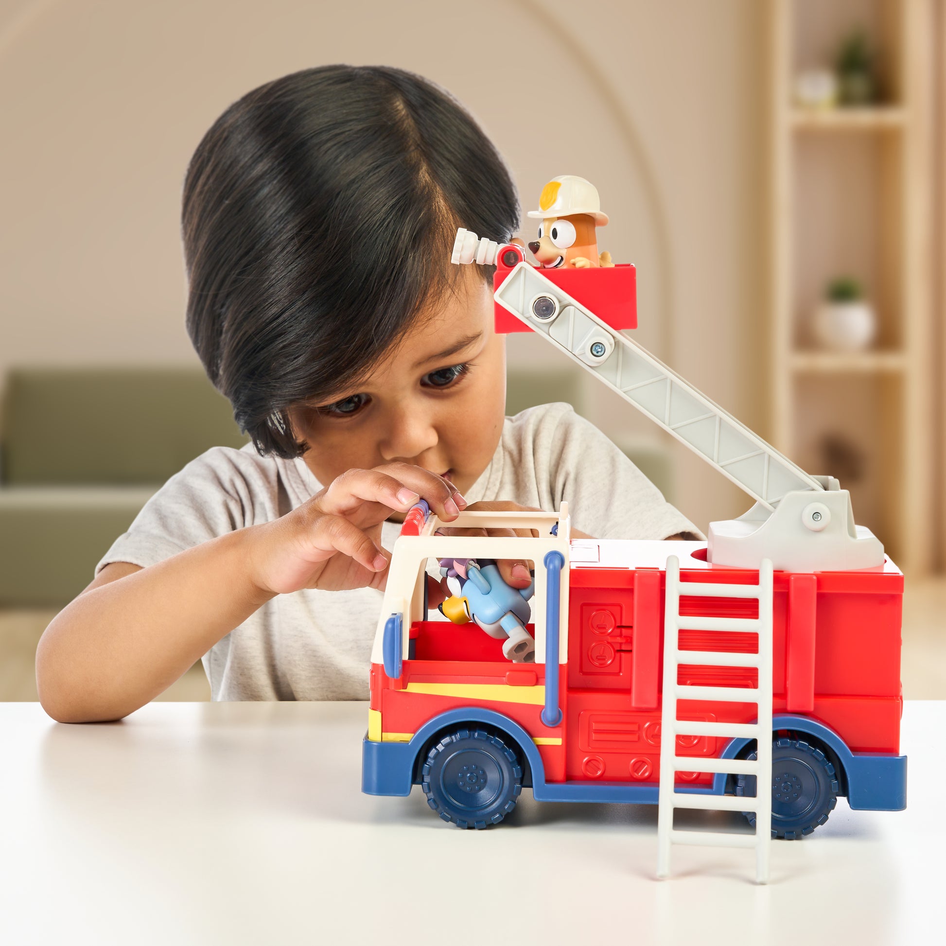 Child playing with a toy fire truck indoors
