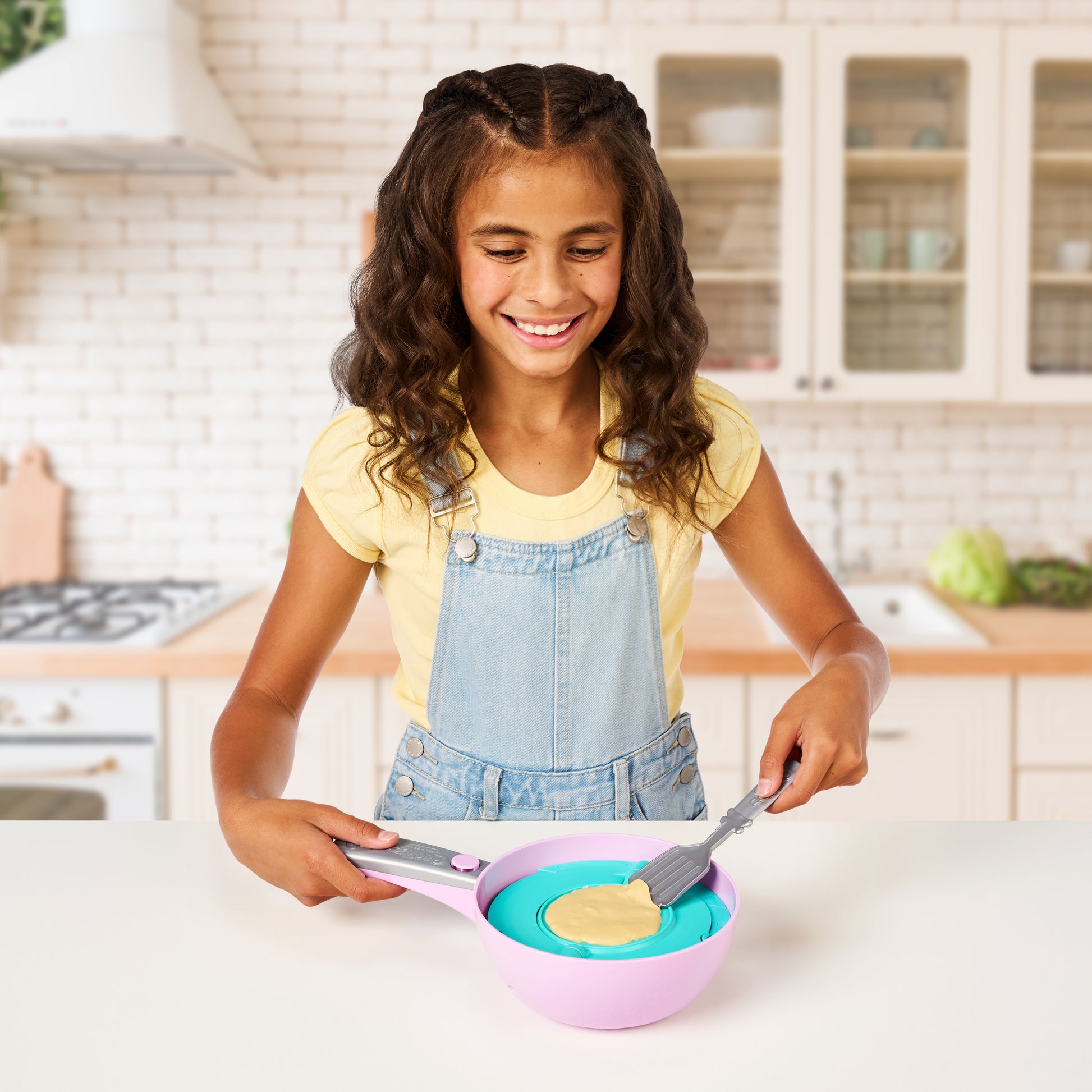 Young girl in a kitchen using a pink and blue toy kitchen set