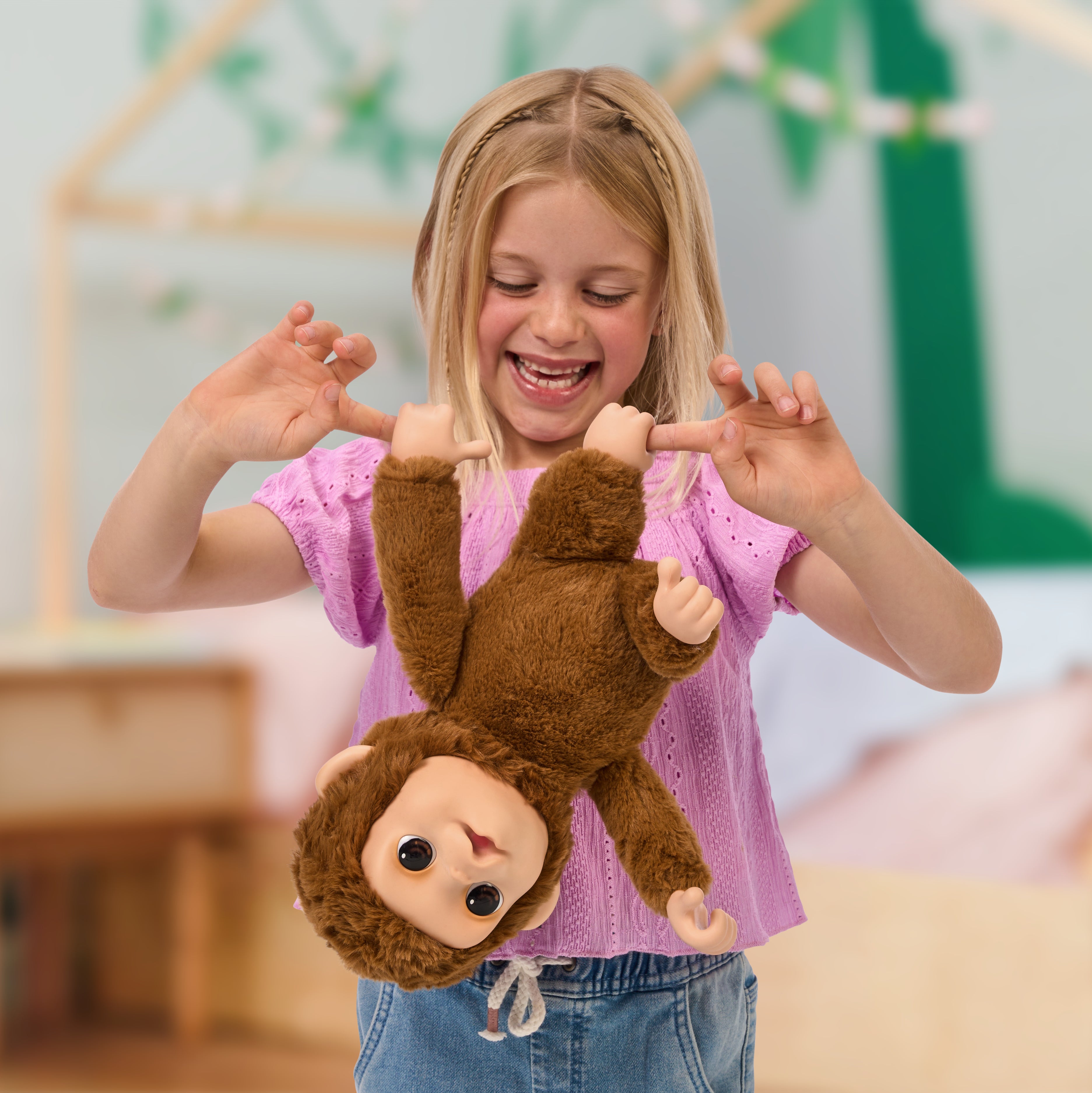 Young girl playing with a plush monkey toy in a room with a blurred background