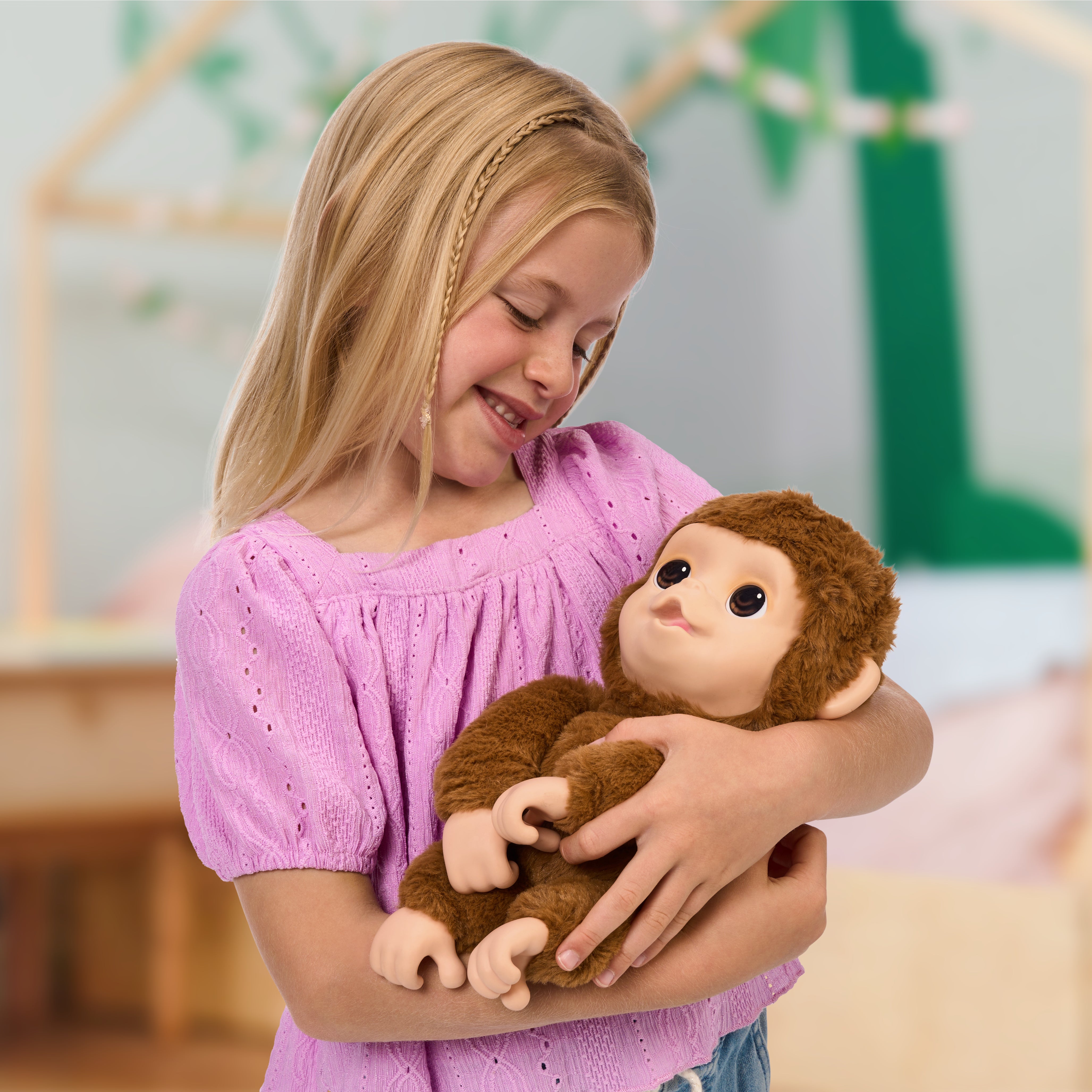 Young girl holding a plush monkey toy in a room with a blurred background