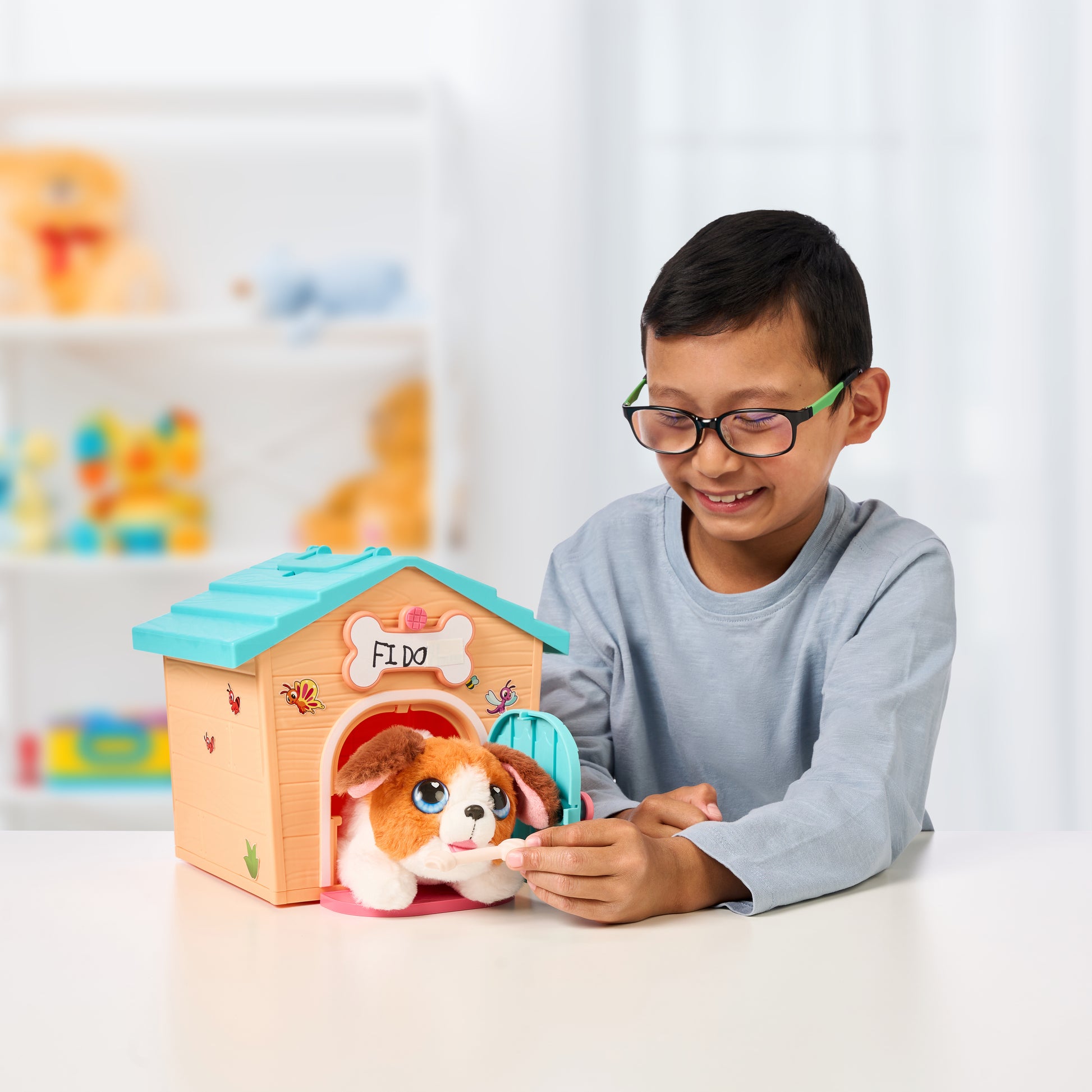 Child playing with a toy dog house and plush dog inside, with a colorful shelf in the background.