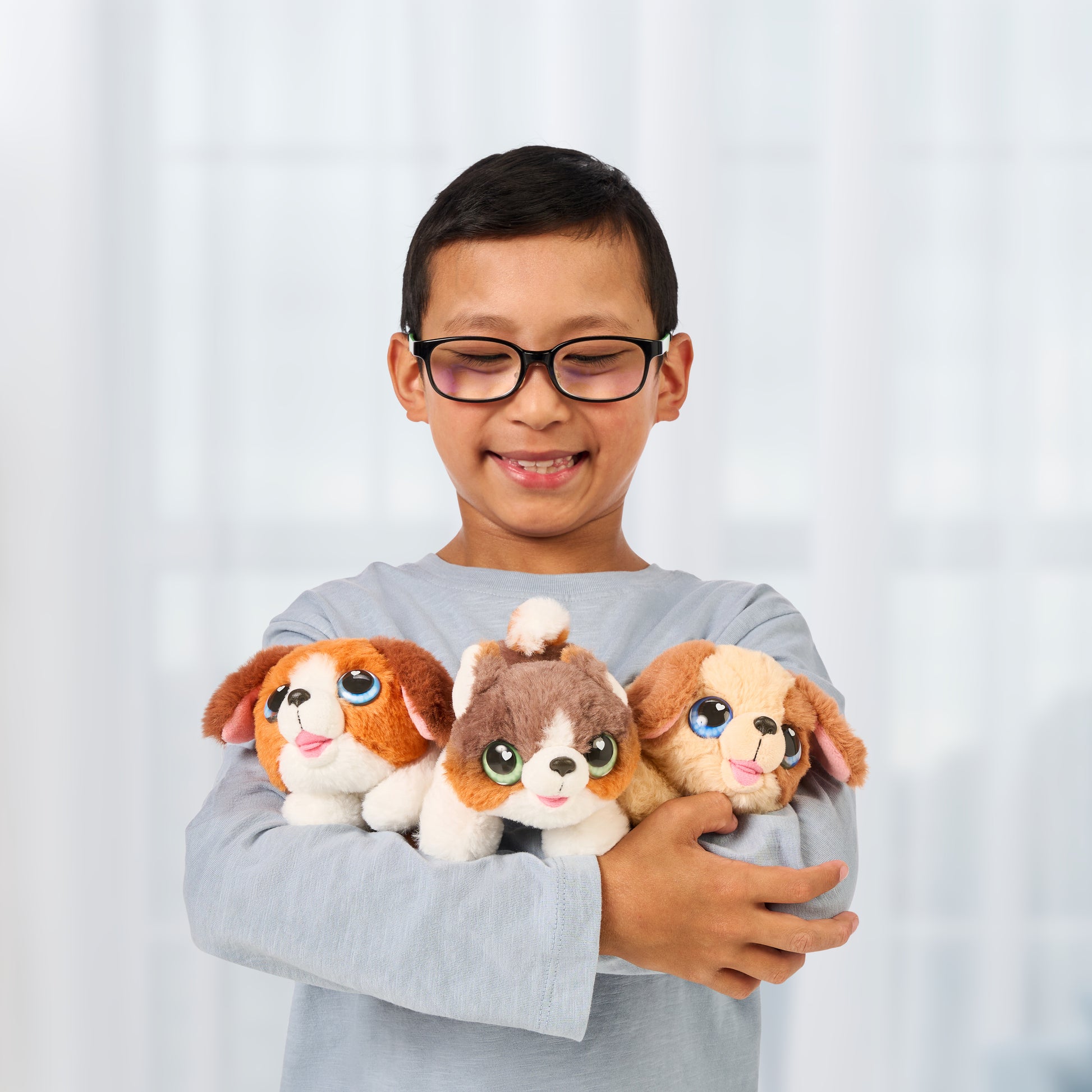 Child holding three plush dog toys against a white background