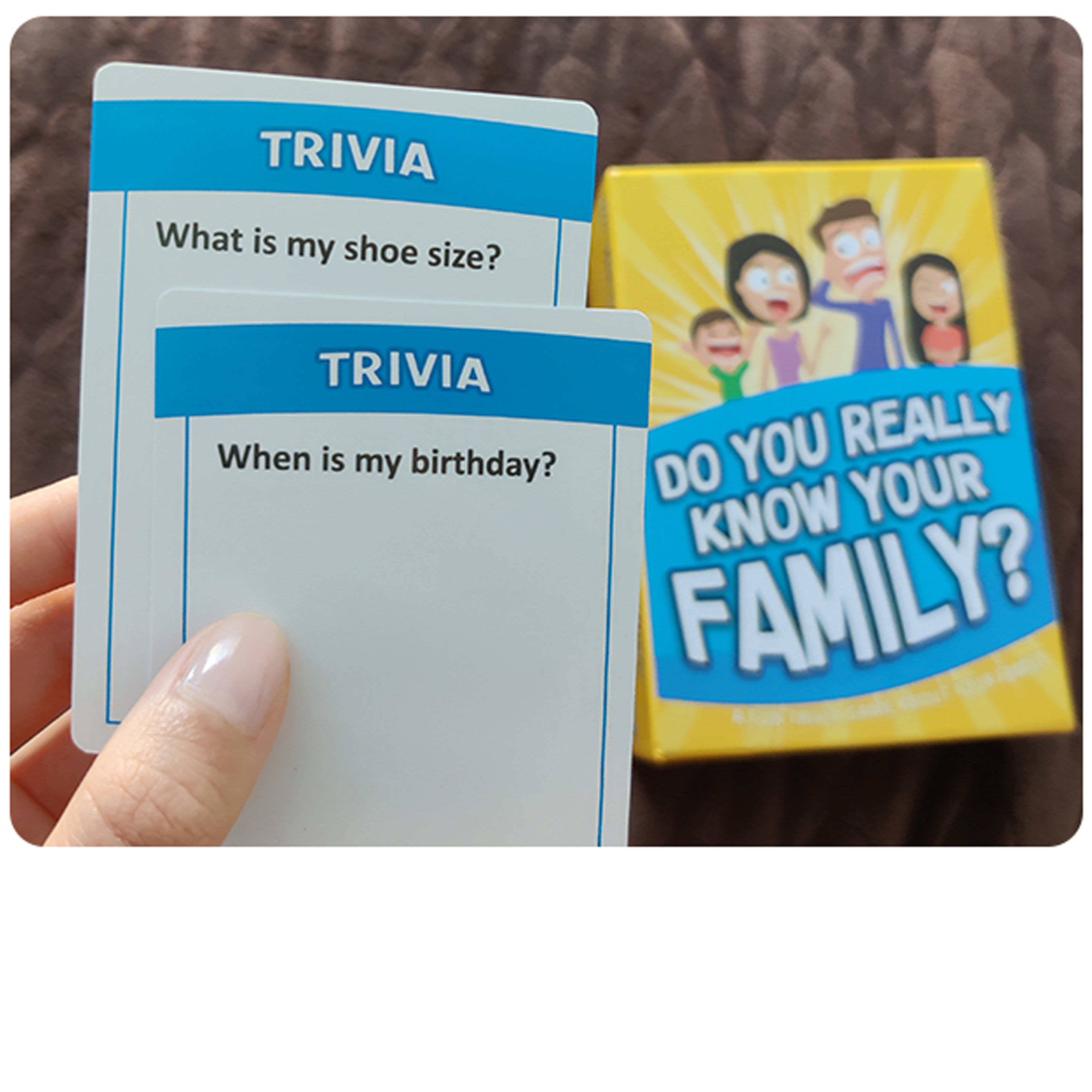 Card game with trivia questions and a family-themed box on a brown surface