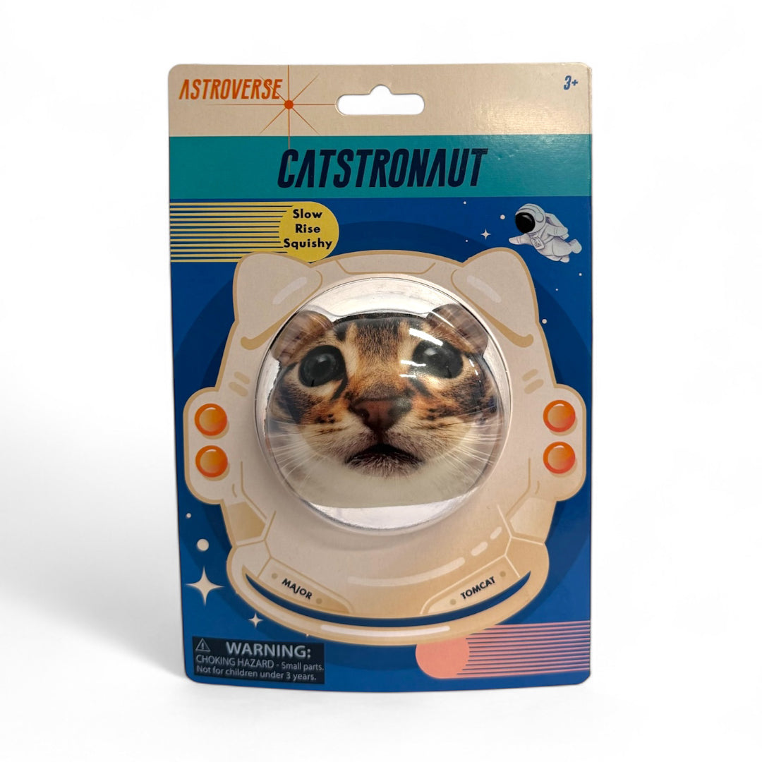 Astroverse Catstronaut is a grip strength toy with a squishy cat face inside an illustrated astronaut helmet, vibrant space-themed graphics, and warning labels on its cardboard backing.