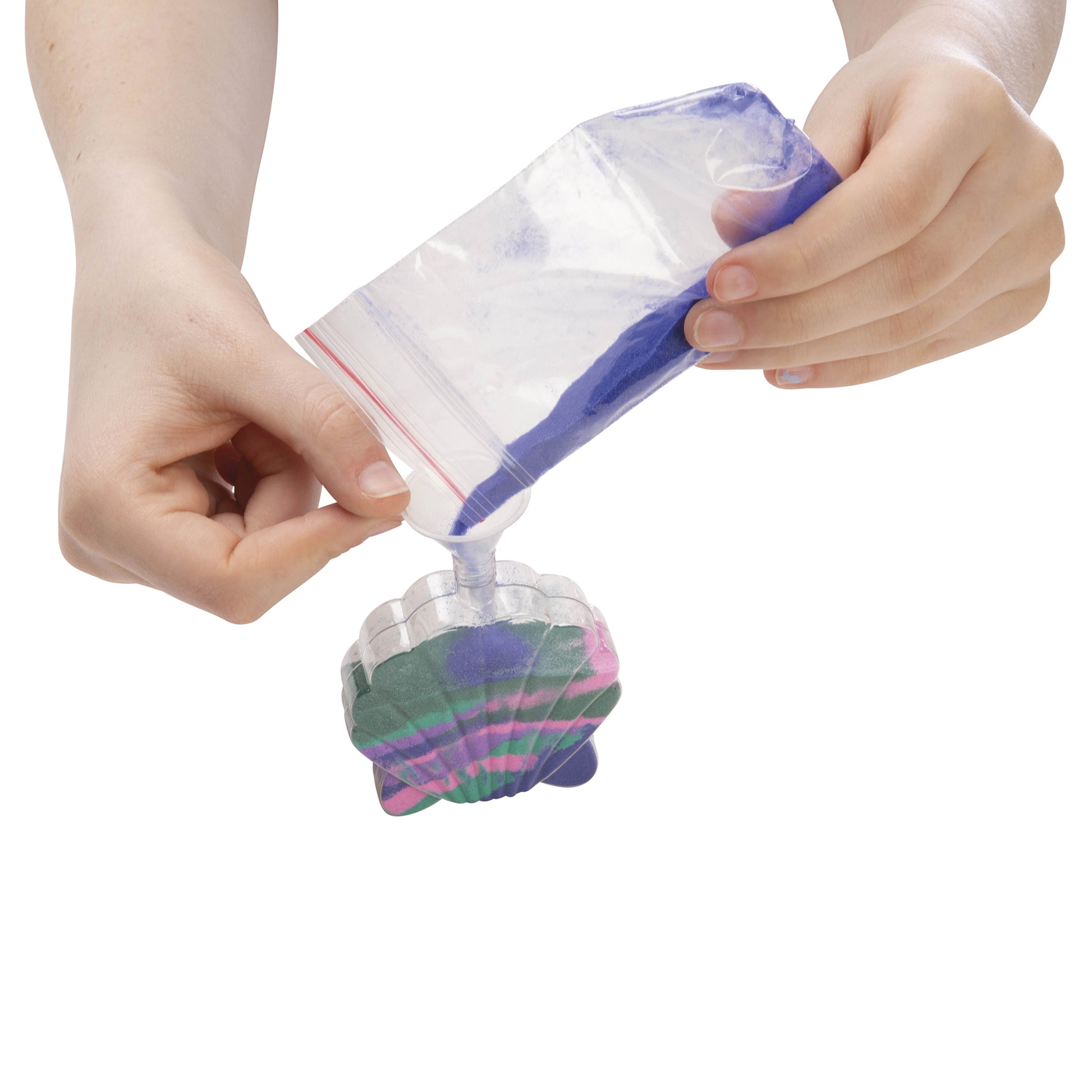 Two hands pour blue and purple sand from a bag into a clear, shell-shaped Mermaid Sand Art container by Toysmith. It's partially filled with colored sand; assorted styles are available, but color selection isn't offered.