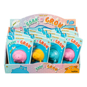 Display box of Toysmith Pet Shop Soak And Grow, featuring blue, pink, and yellow hedgehog water-activated grow toys in individual packages, designed for children ages 5 and up.