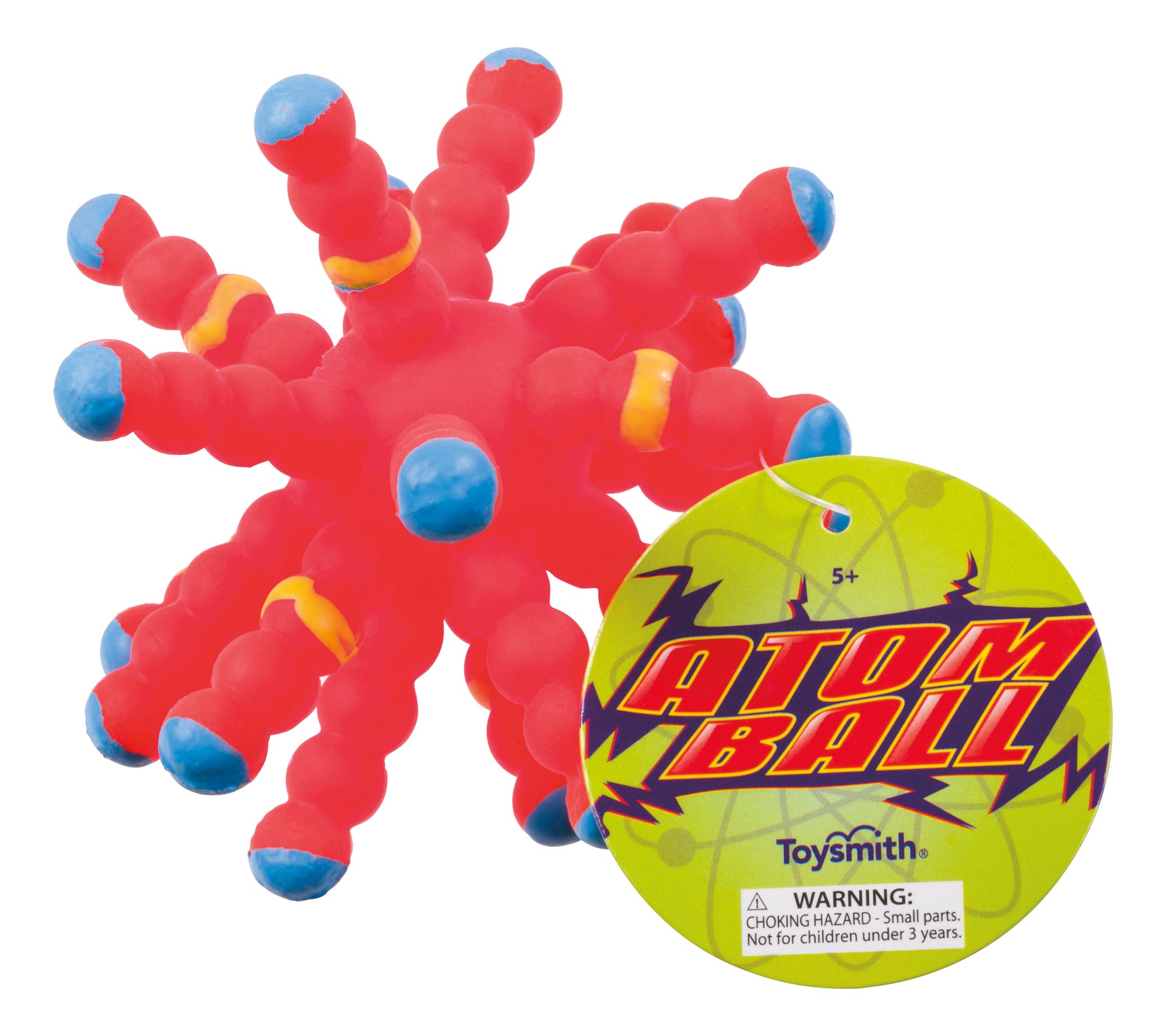 A red rubber Toysmith Colorful Atom Ball with blue and yellow-tipped spikes, featuring a round yellow tag that shows "Atom Ball," the Toysmith brand, and a choking hazard warning.