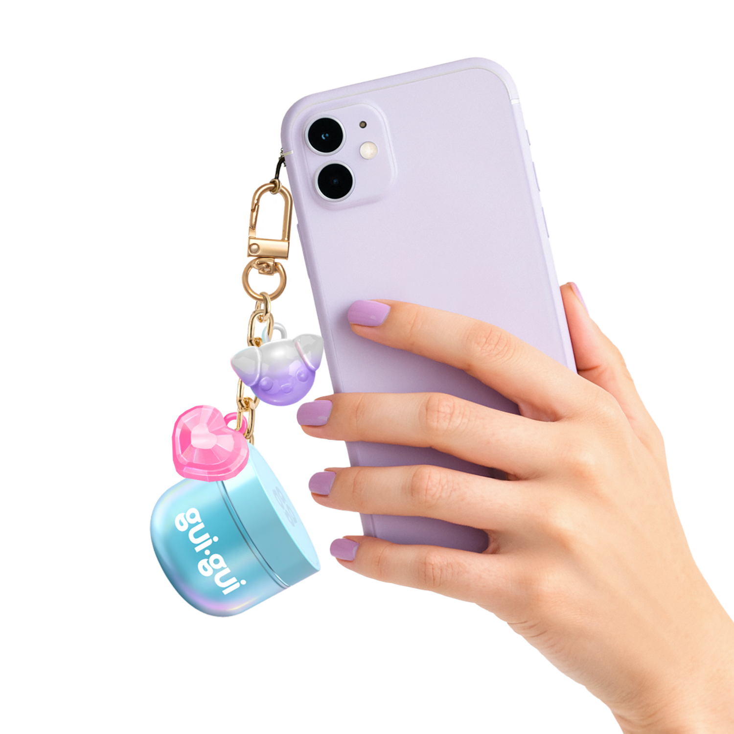 A hand with pastel purple nail polish holds a lavender smartphone with a matching case, featuring a Moose Toys Gui Gui Mini Backpack Charm Slime keychain, along with a pink heart and a silver-and-purple accessory.
