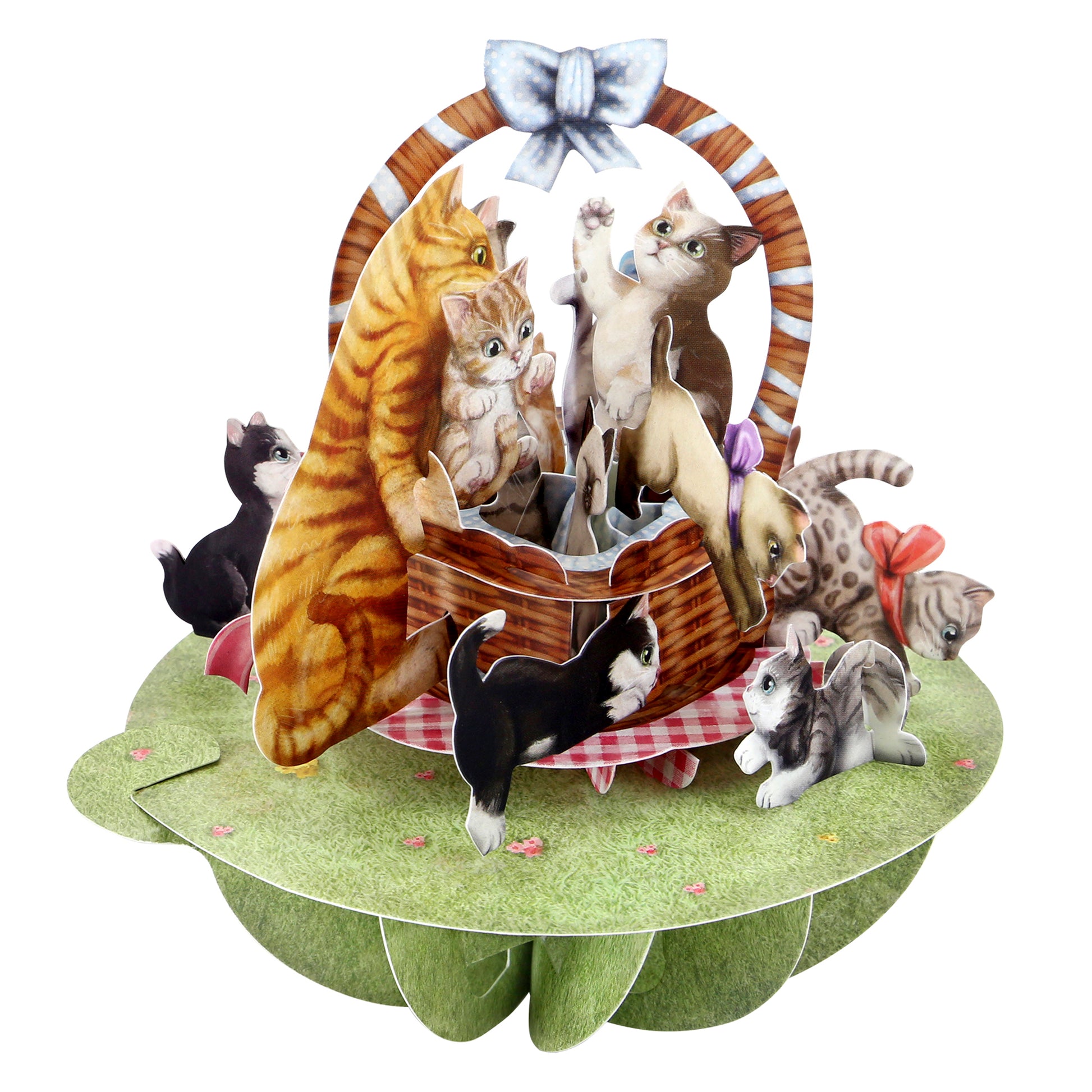 The Santoro Pirouette Card: Kittens in a Basket features playful cats and kittens around a picnic basket on grass, with a blue bow on the handle and a red-checkered cloth beneath.