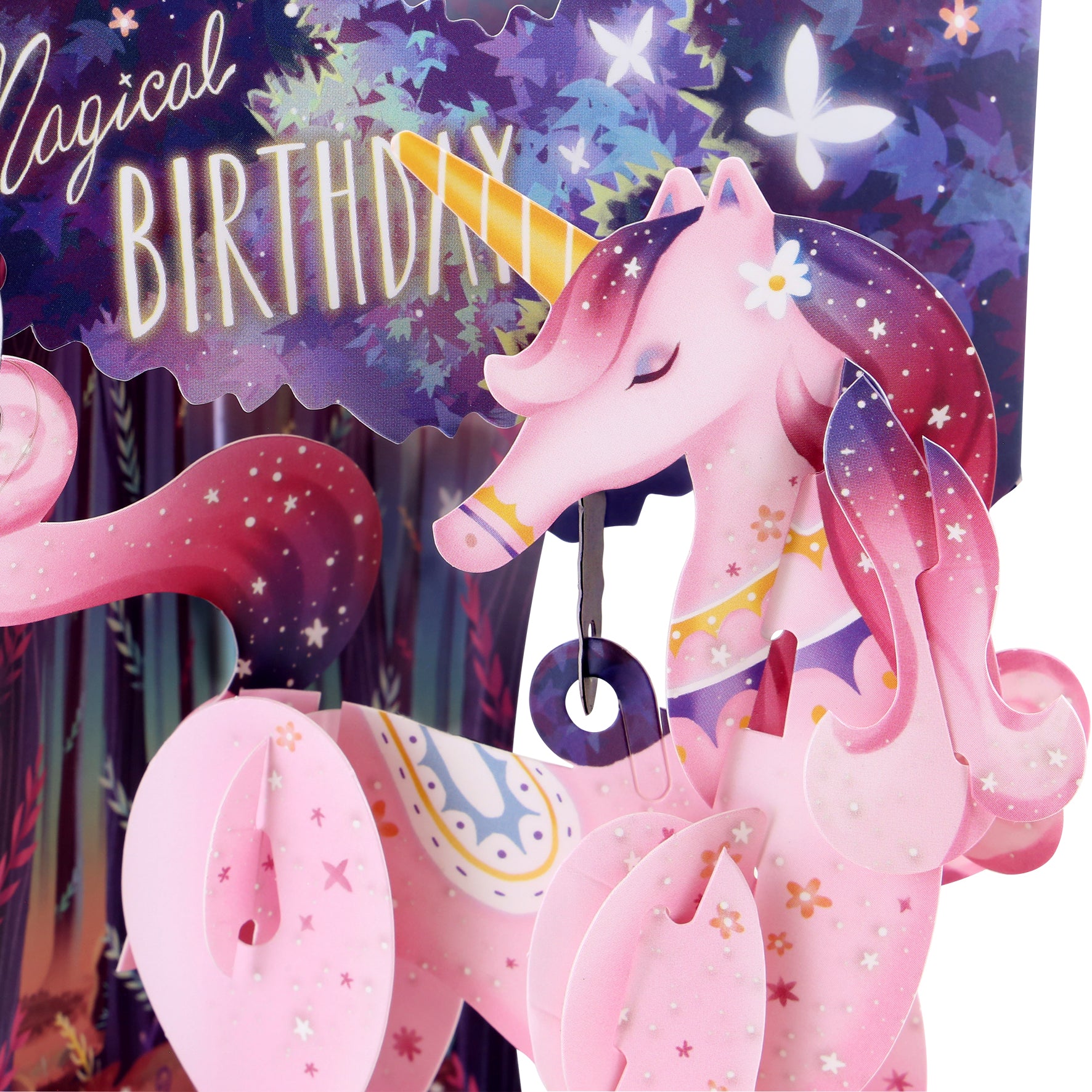 A close-up of the Santoro Swing Card: Magical Birthday Unicorn shows a pink unicorn with a golden horn, stars, and flowers, set before a vibrant "Magical Birthday" sign with butterflies and a forest backdrop.